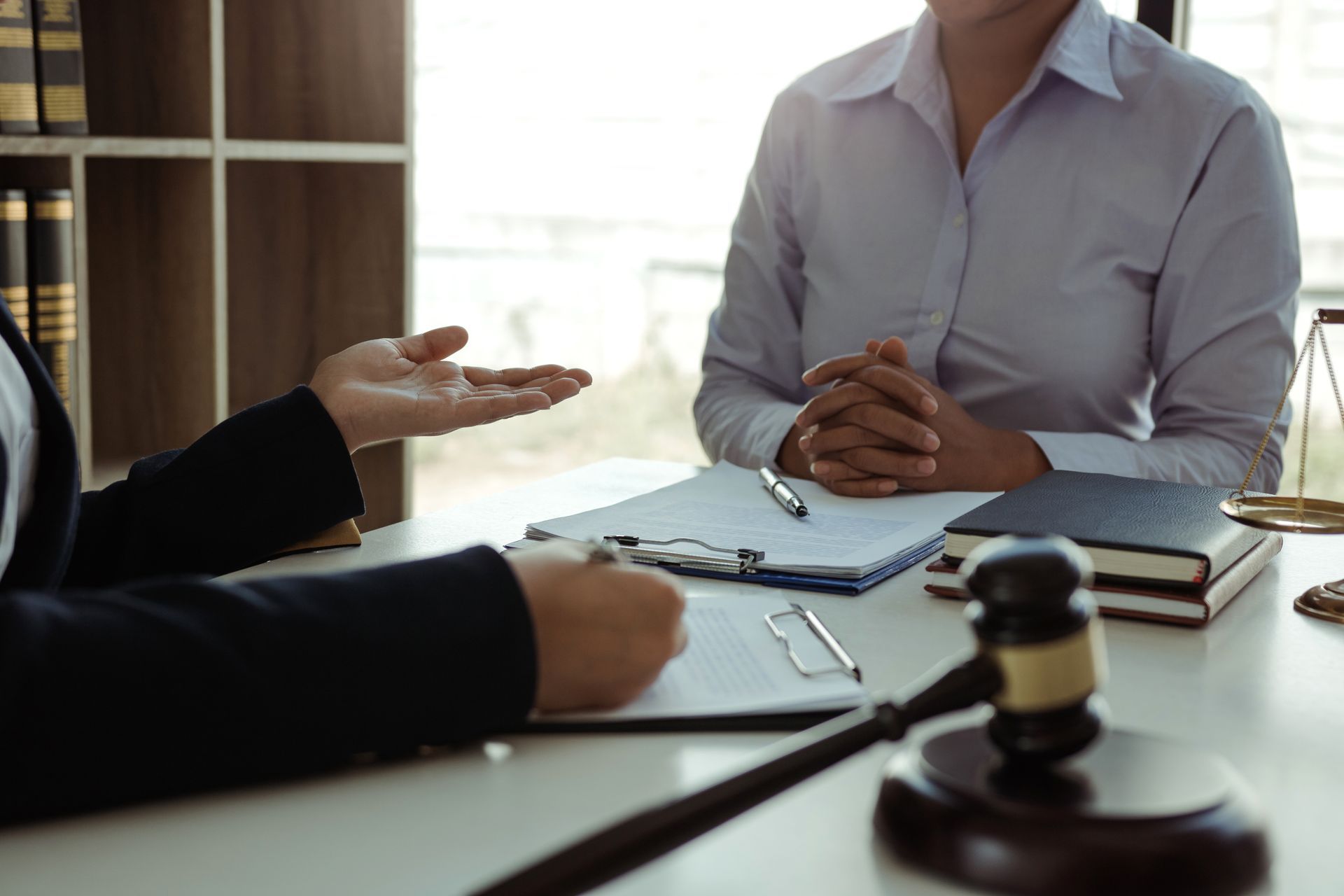 Business meeting with two people at a table, documents, a gavel, and a notebook in the foreground.