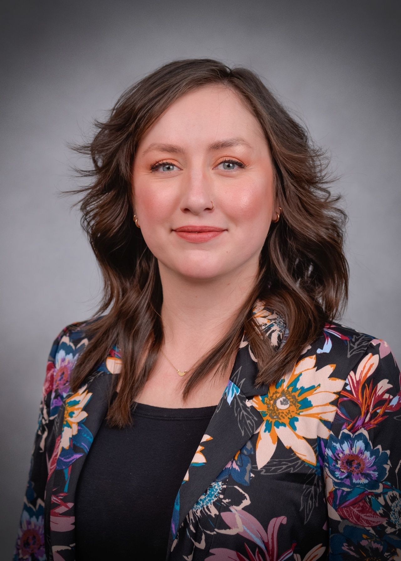 A woman is wearing a floral jacket and a black shirt.