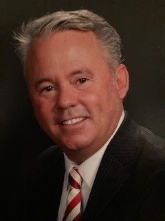 A man in a suit and tie is smiling for the camera.