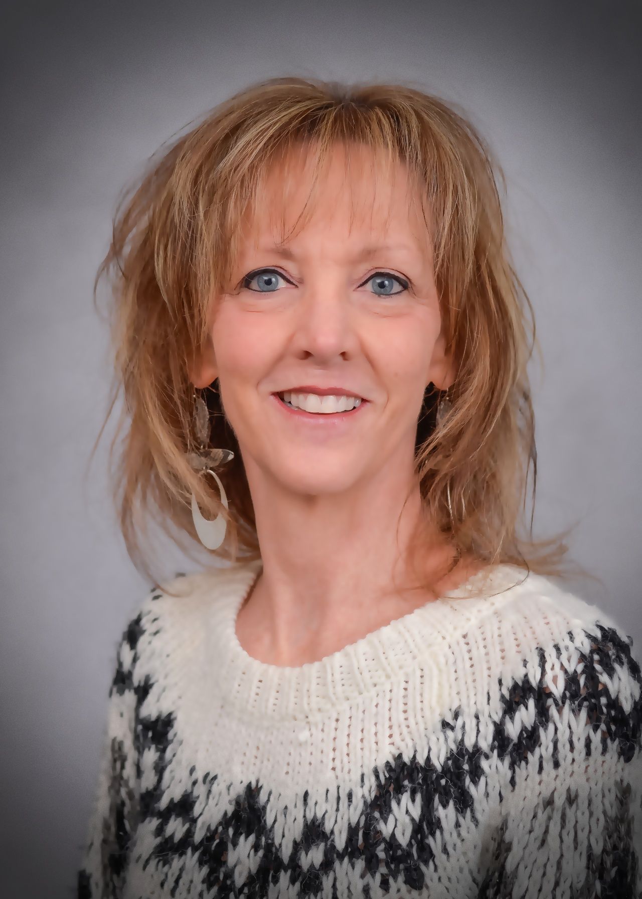 A woman is wearing a sweater and smiling for the camera.
