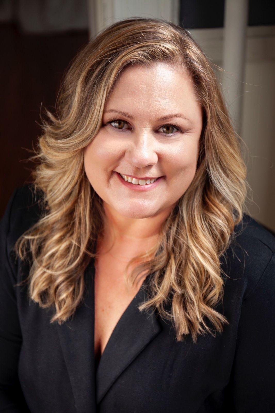A woman in a black jacket is smiling for the camera.