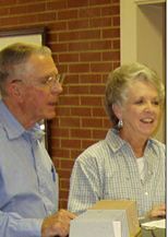 A man and a woman are standing next to each other in front of a brick wall.
