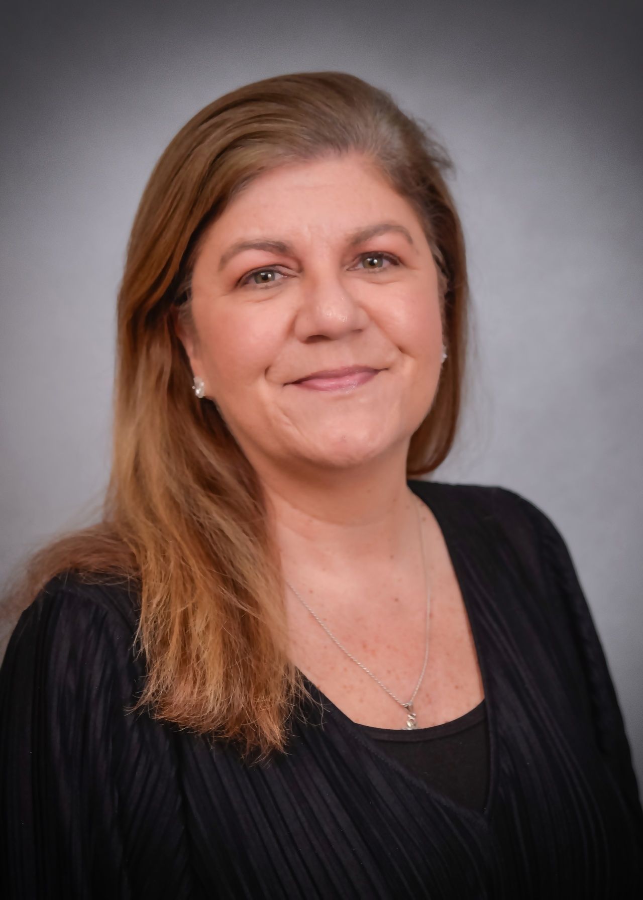A woman in a black shirt is smiling for the camera.