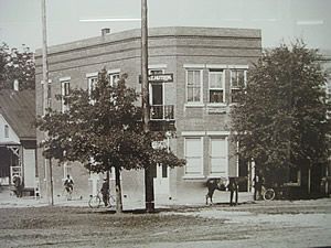 A black and white photo of a brick building with a sign on the side that says one way