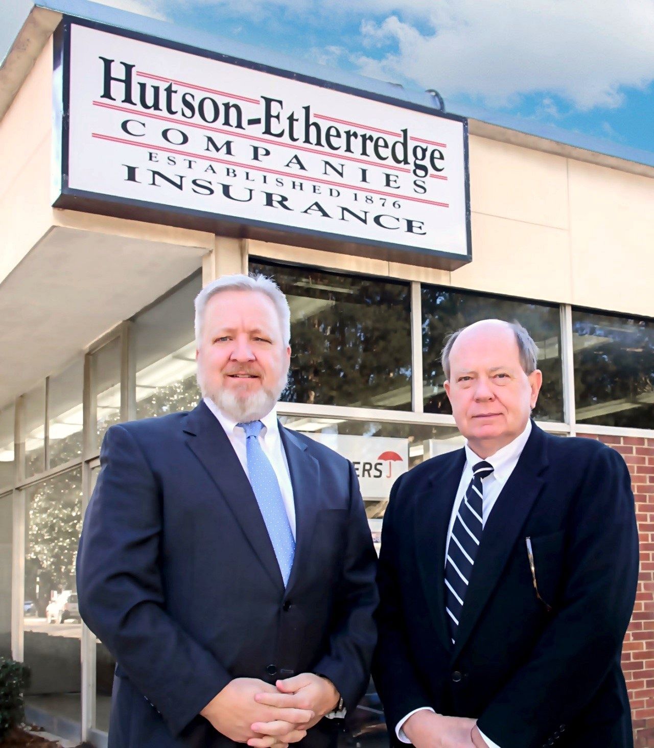 Two men standing in front of a hutson etheredge company