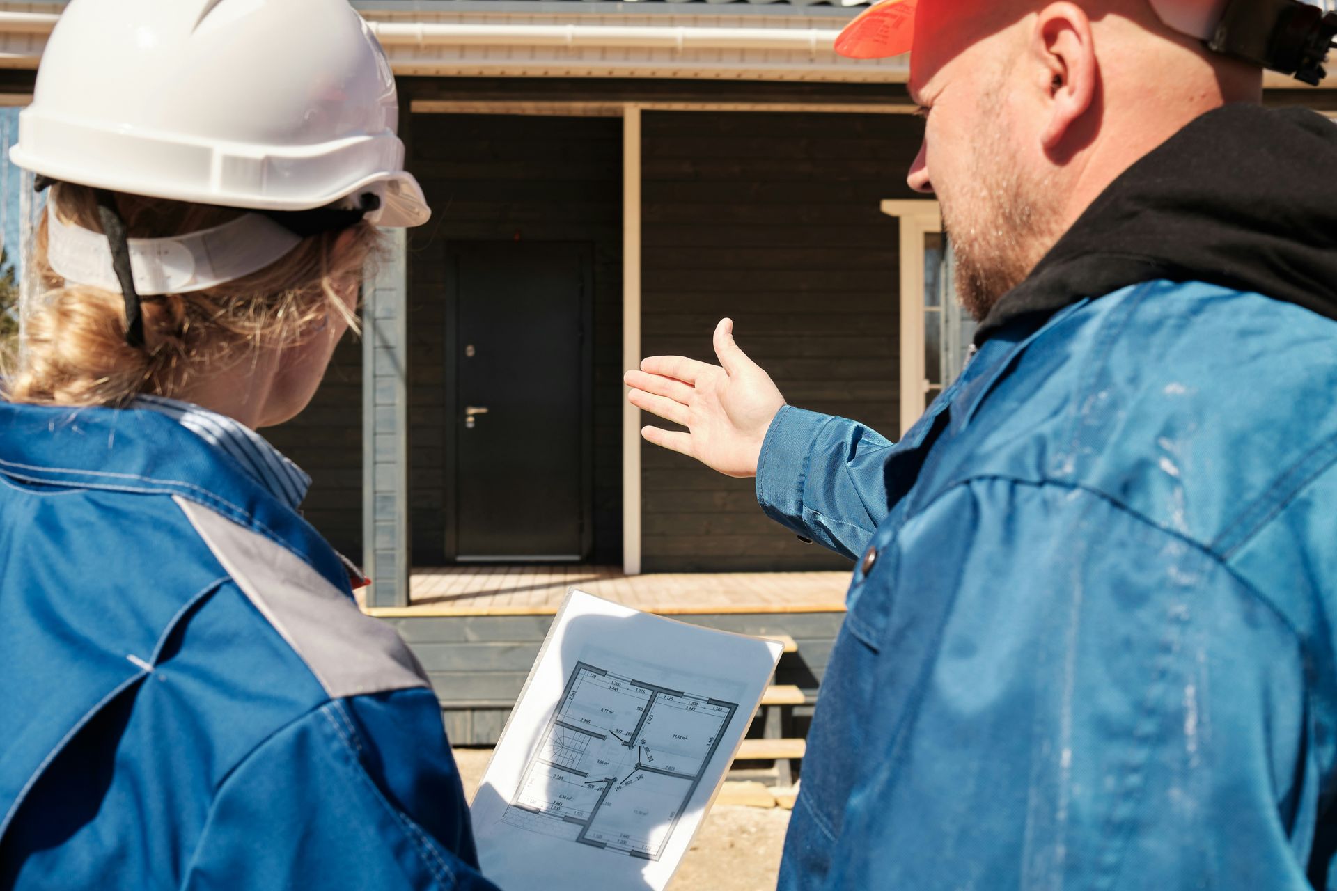 A man and a woman are looking at a blueprint of a house.