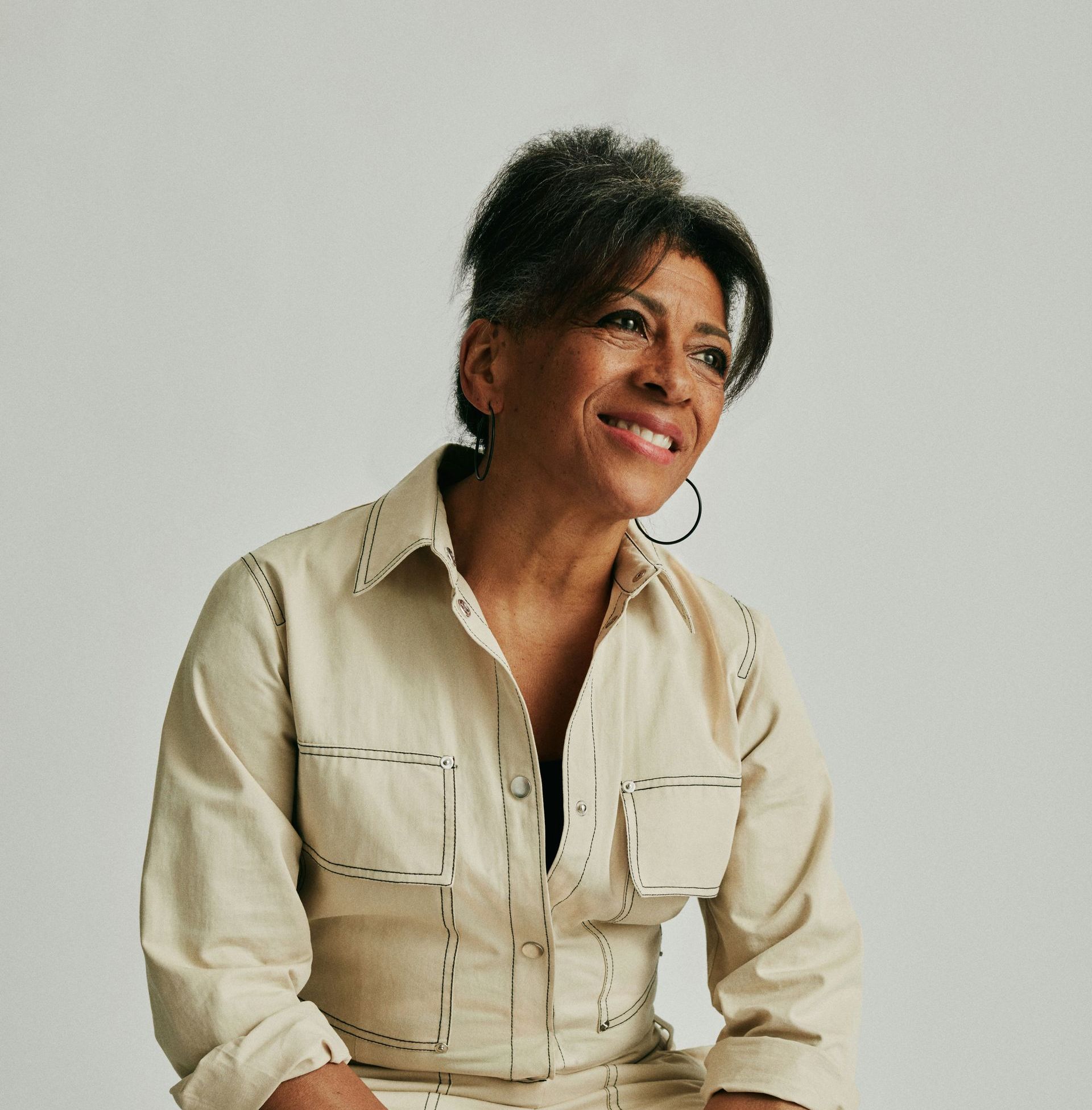 A woman wearing a white shirt and hoop earrings is smiling