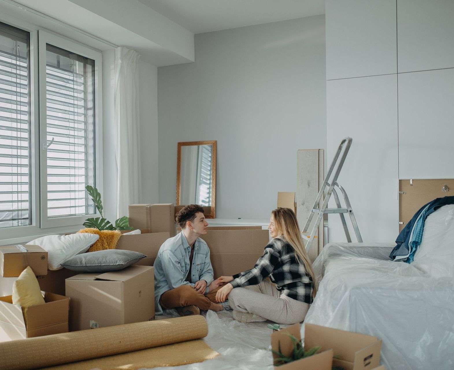 A man and a woman are sitting on a couch in a room filled with boxes.
