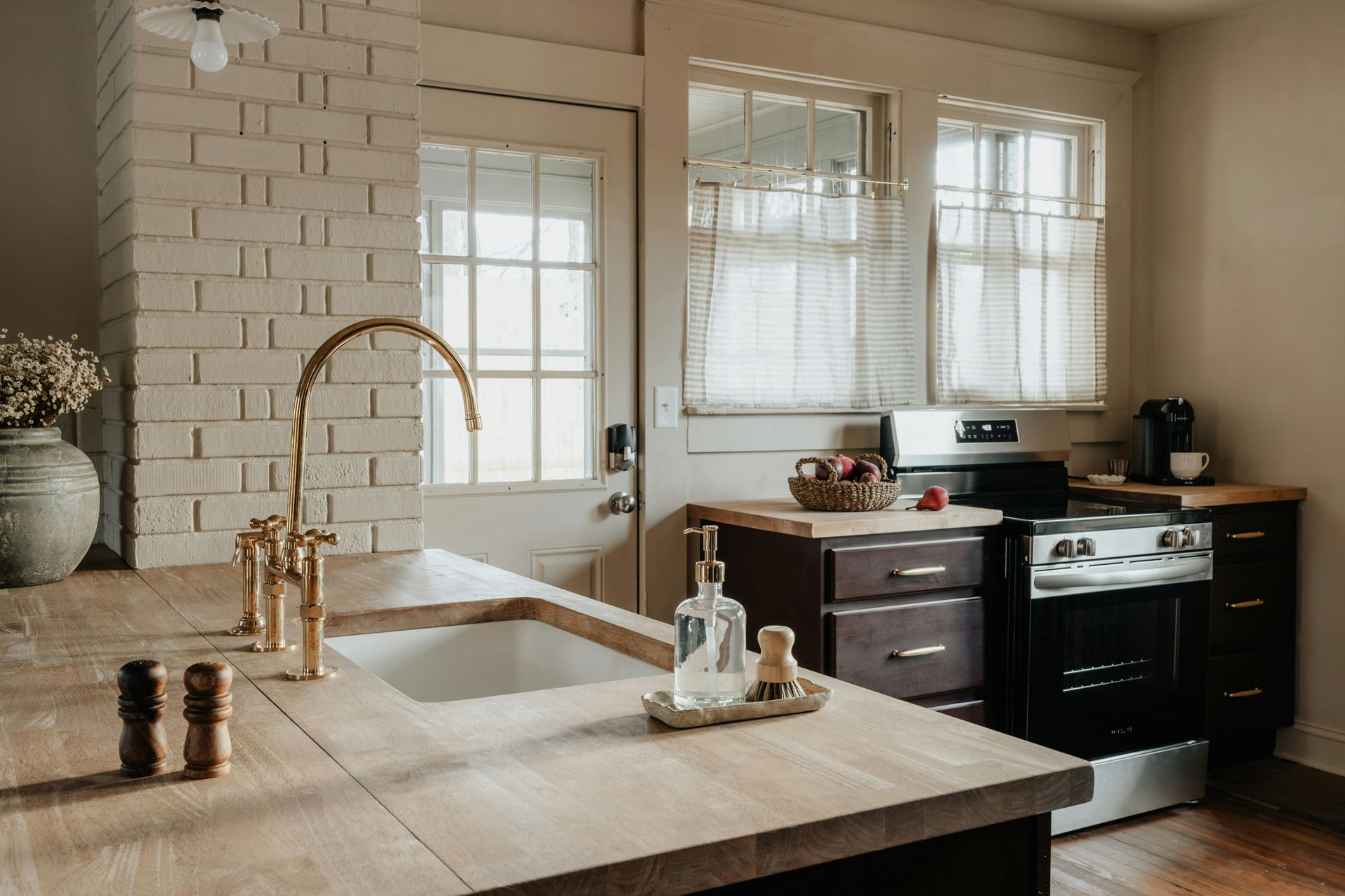 A kitchen with a sink , stove , and window.