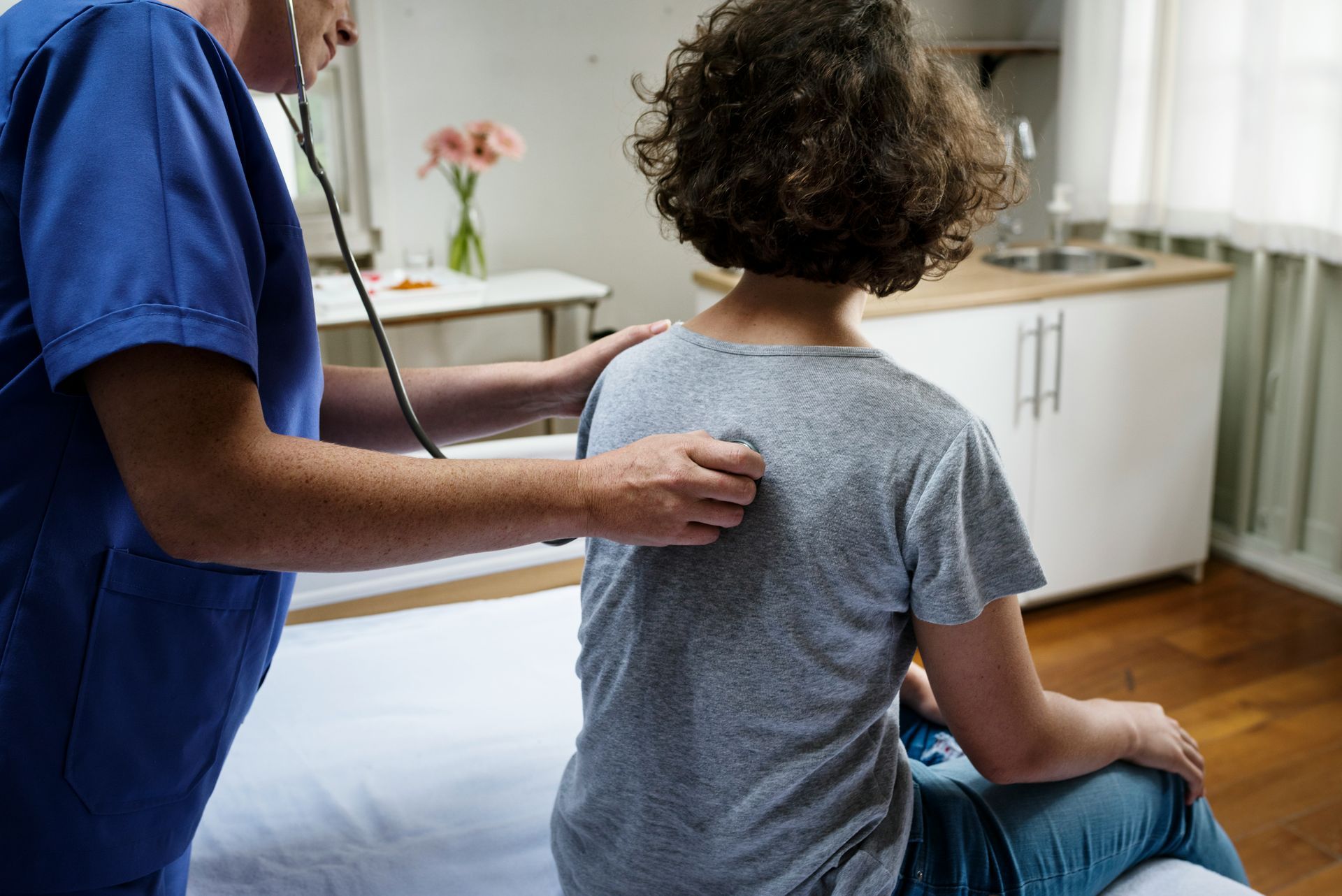 A doctor is listening to a patient 's lungs with a stethoscope.