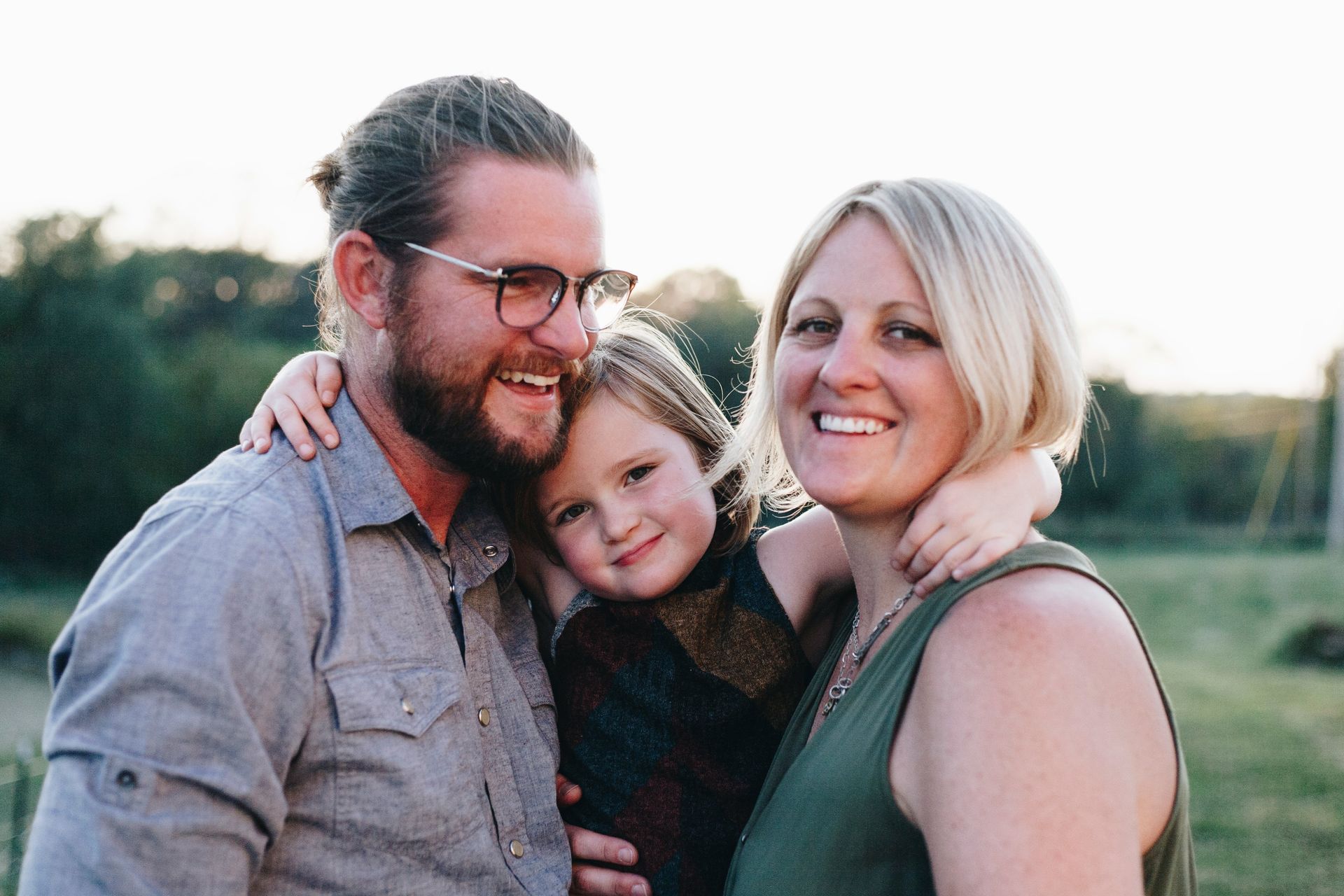 A man , woman and child are posing for a picture in a field.