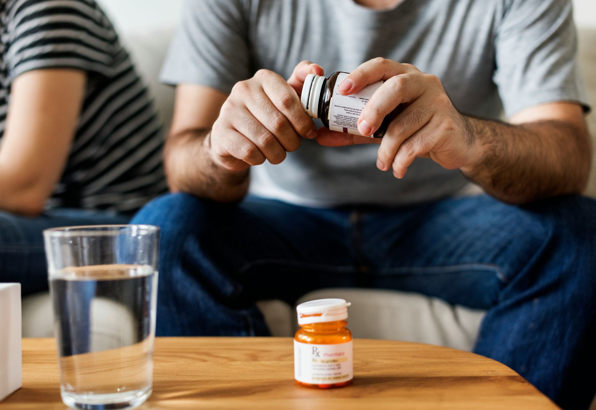 A man is pouring pills into a glass of water.