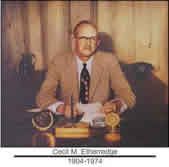 A man in a suit and tie is sitting at a desk.