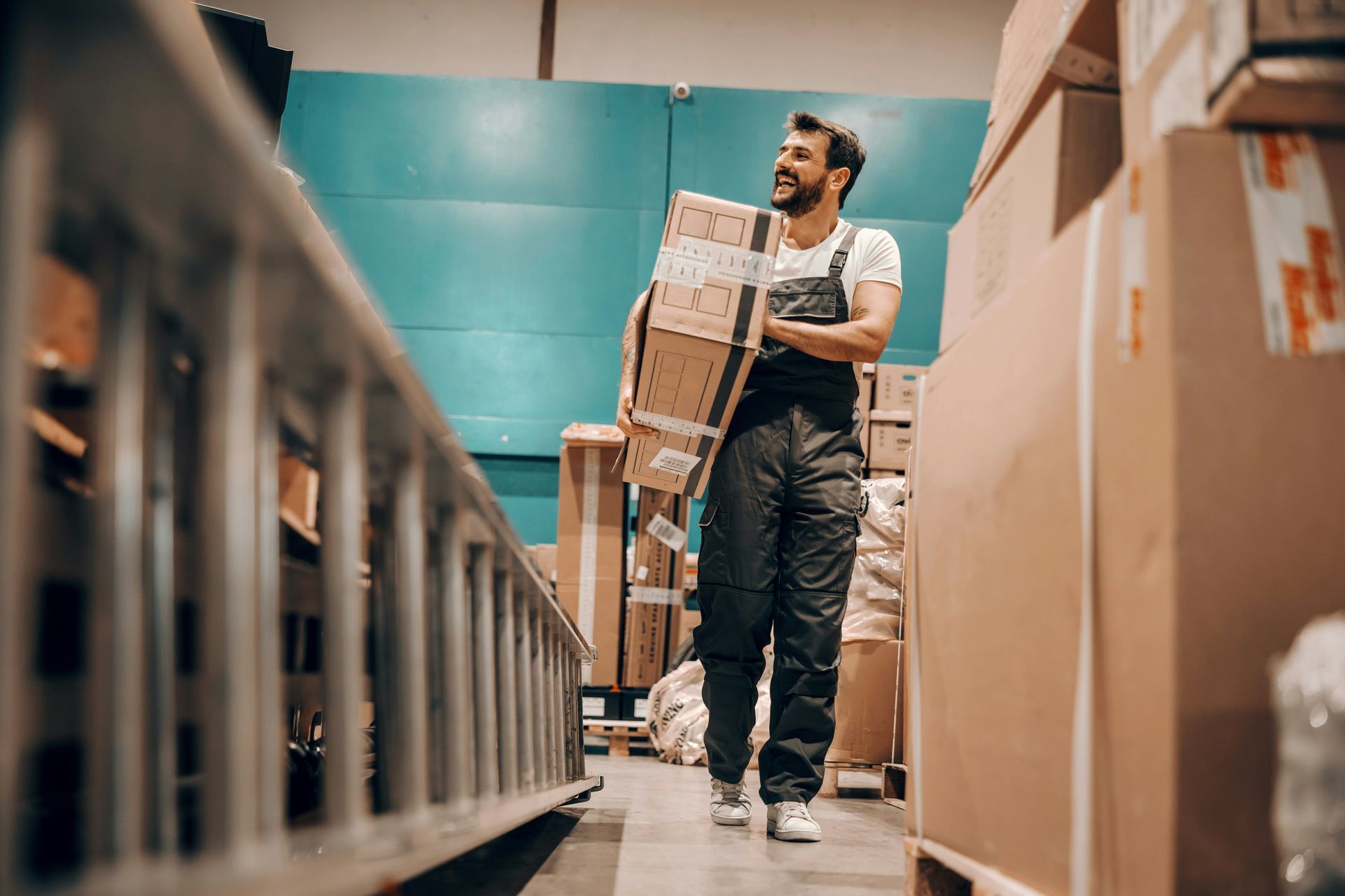 A man is carrying a box in a warehouse.