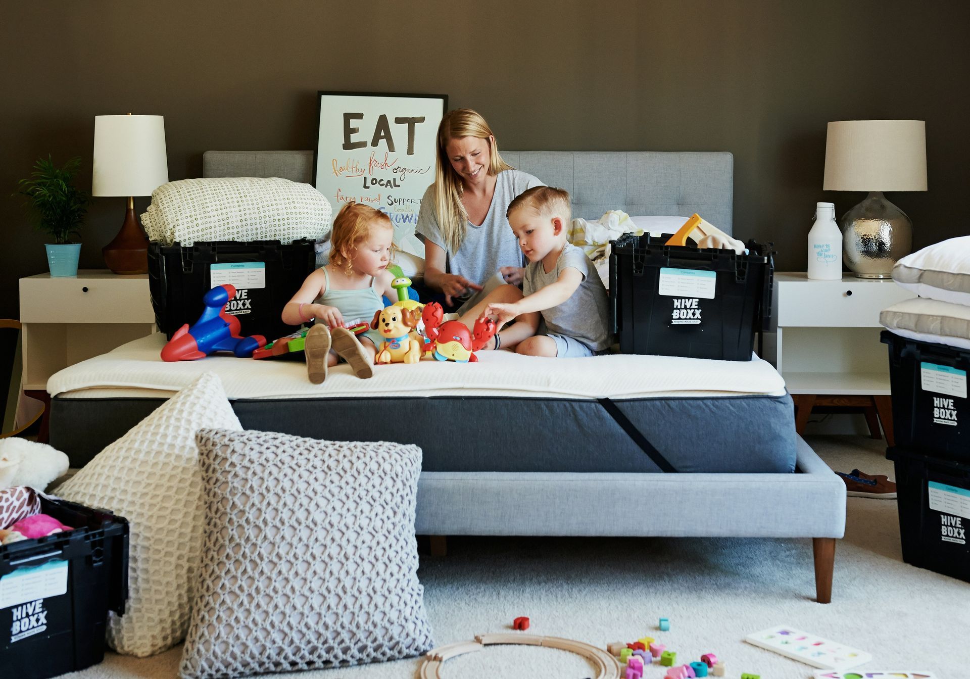 A woman and two children are sitting on a bed playing with toys.