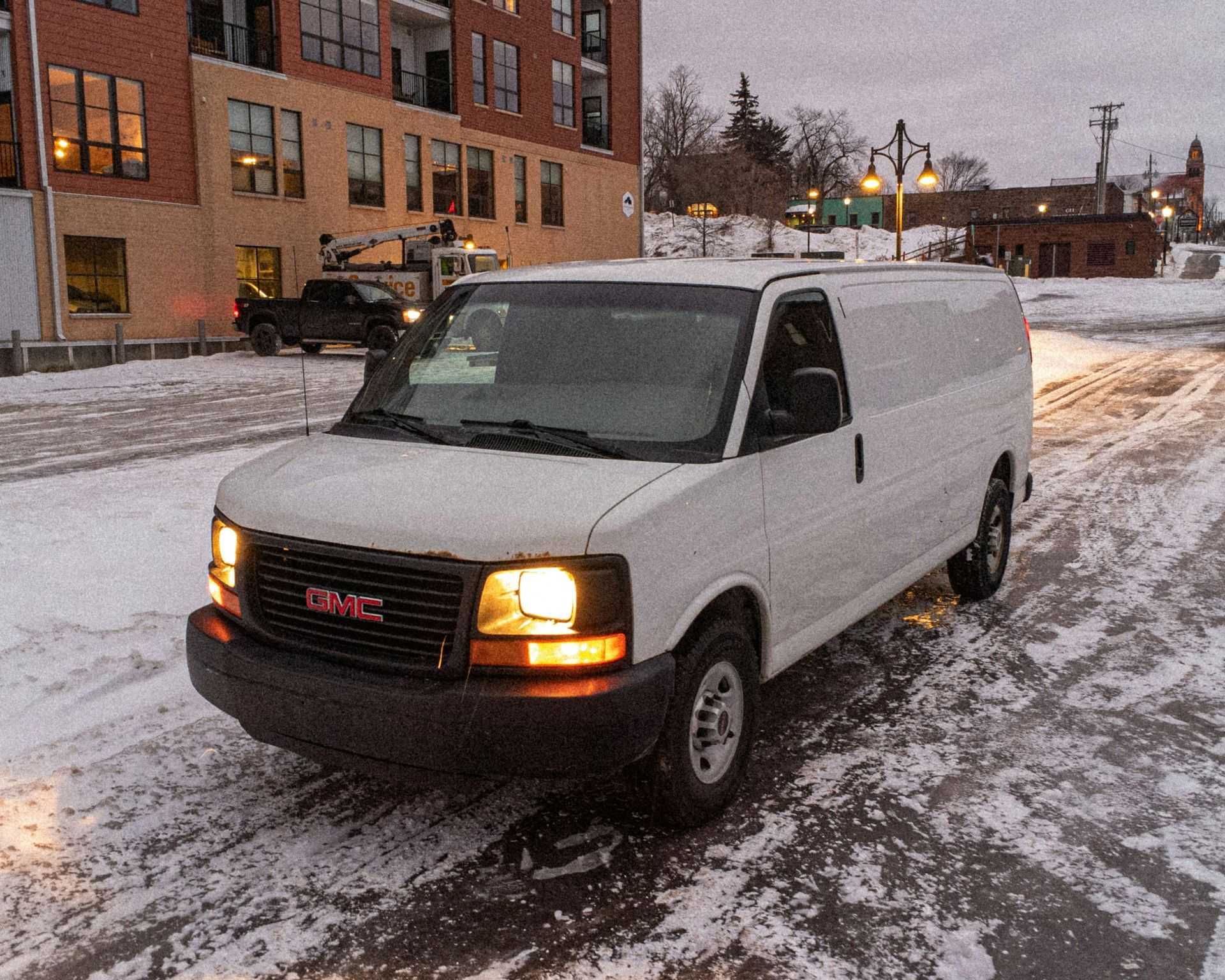 A white gmc van is parked in the snow