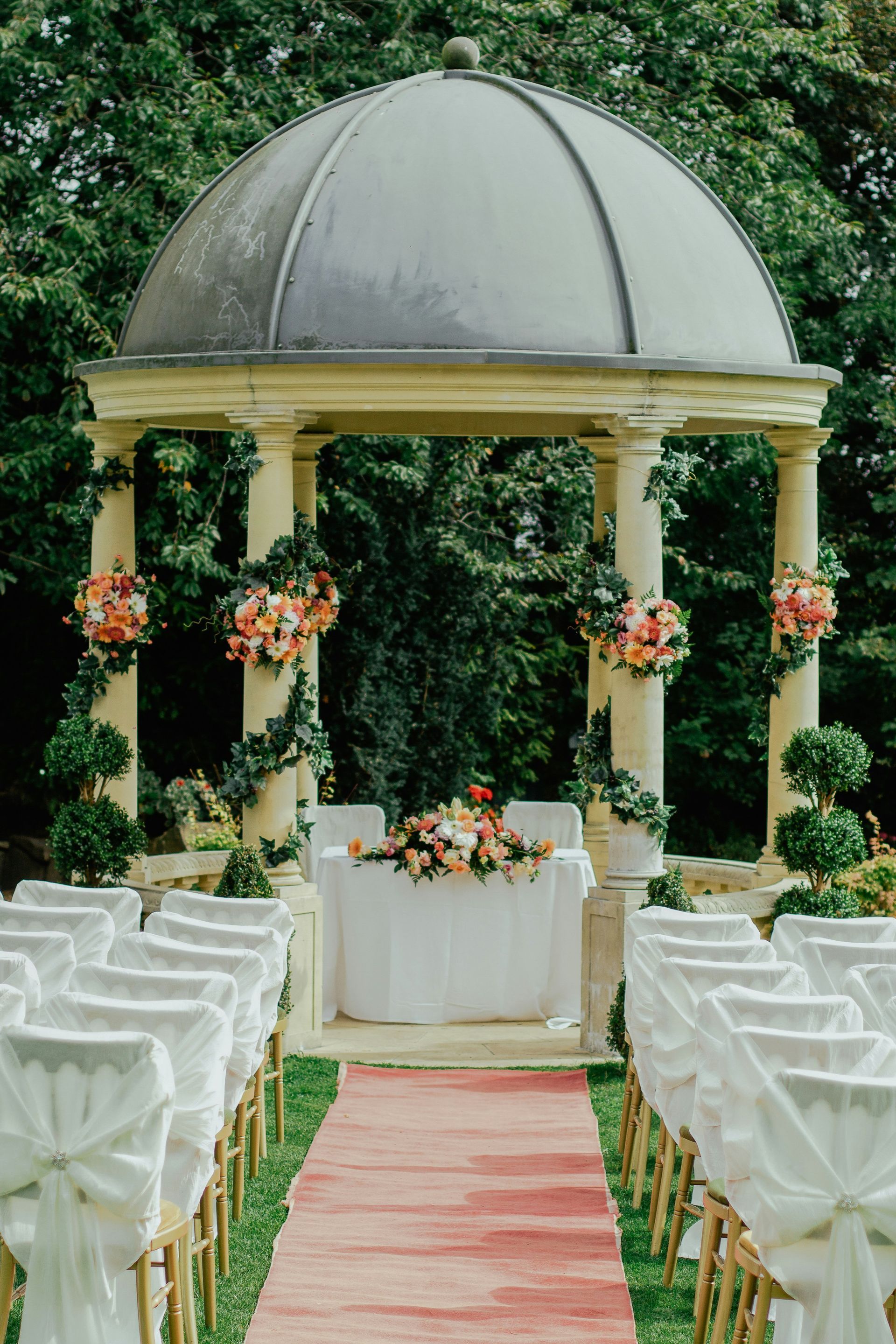 A wedding ceremony is taking place in front of a gazebo.