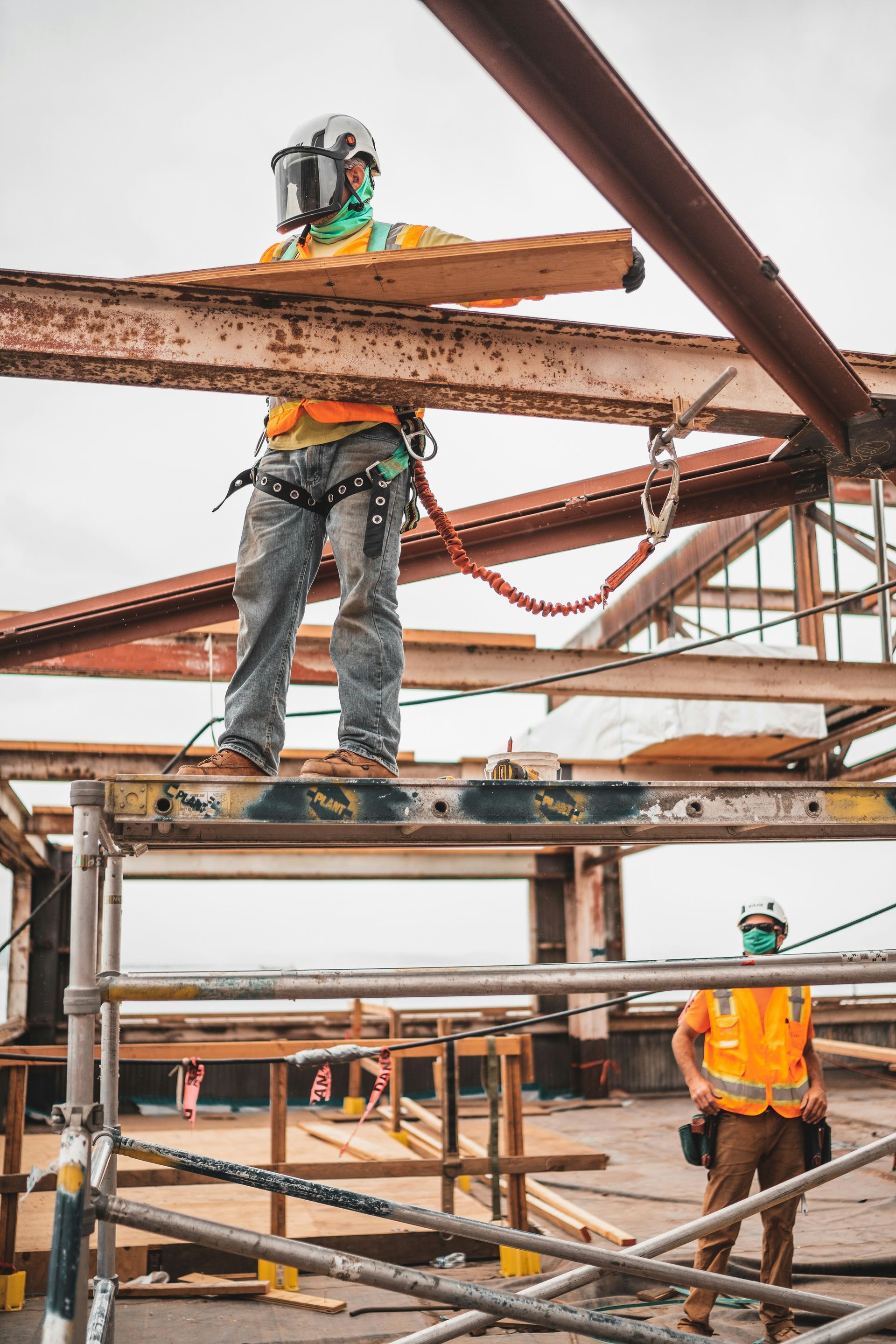 A construction worker is standing on top of a scaffolding.