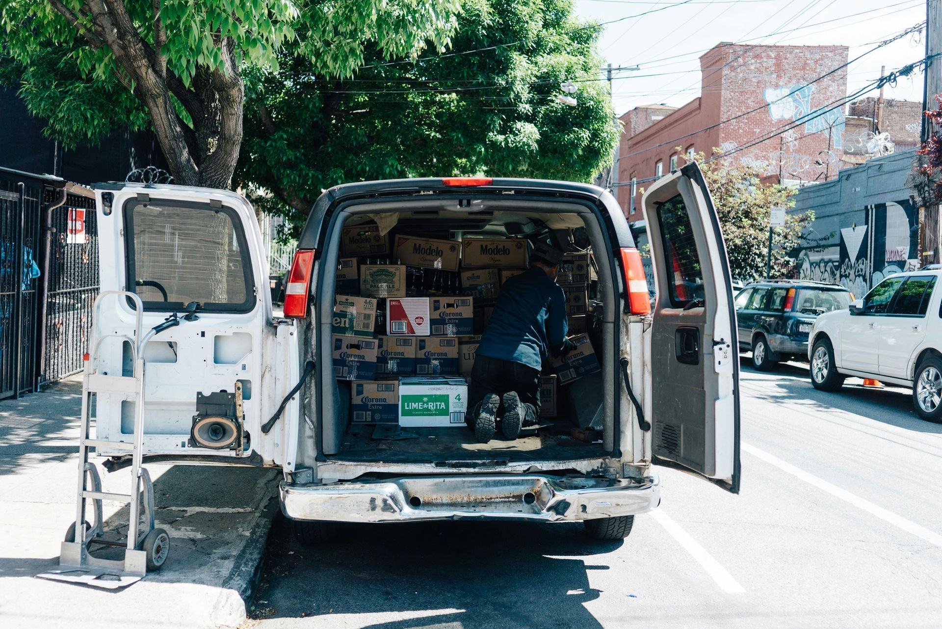 A white van is parked on the side of the road with its doors open.