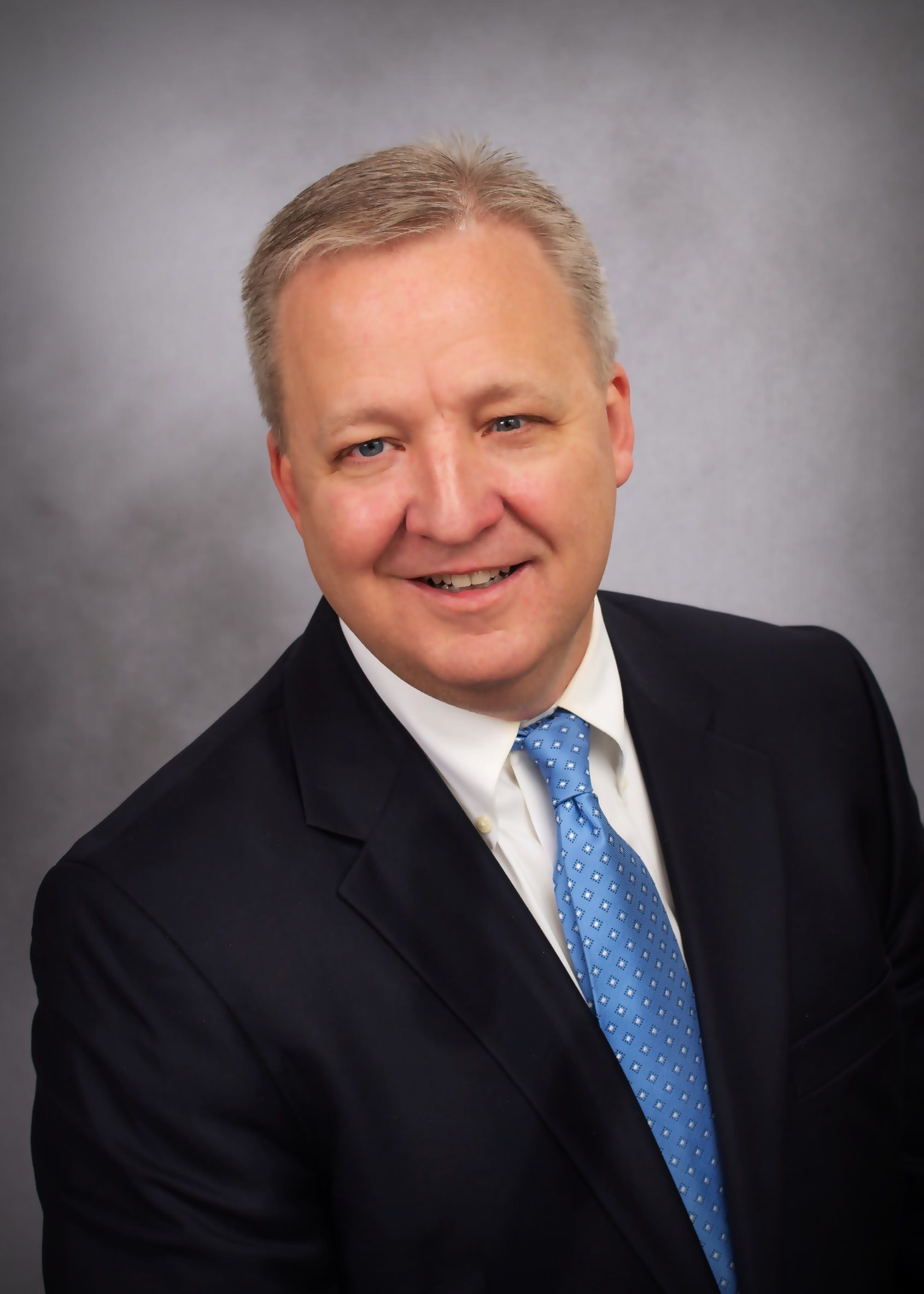 A man in a suit and tie is smiling for the camera