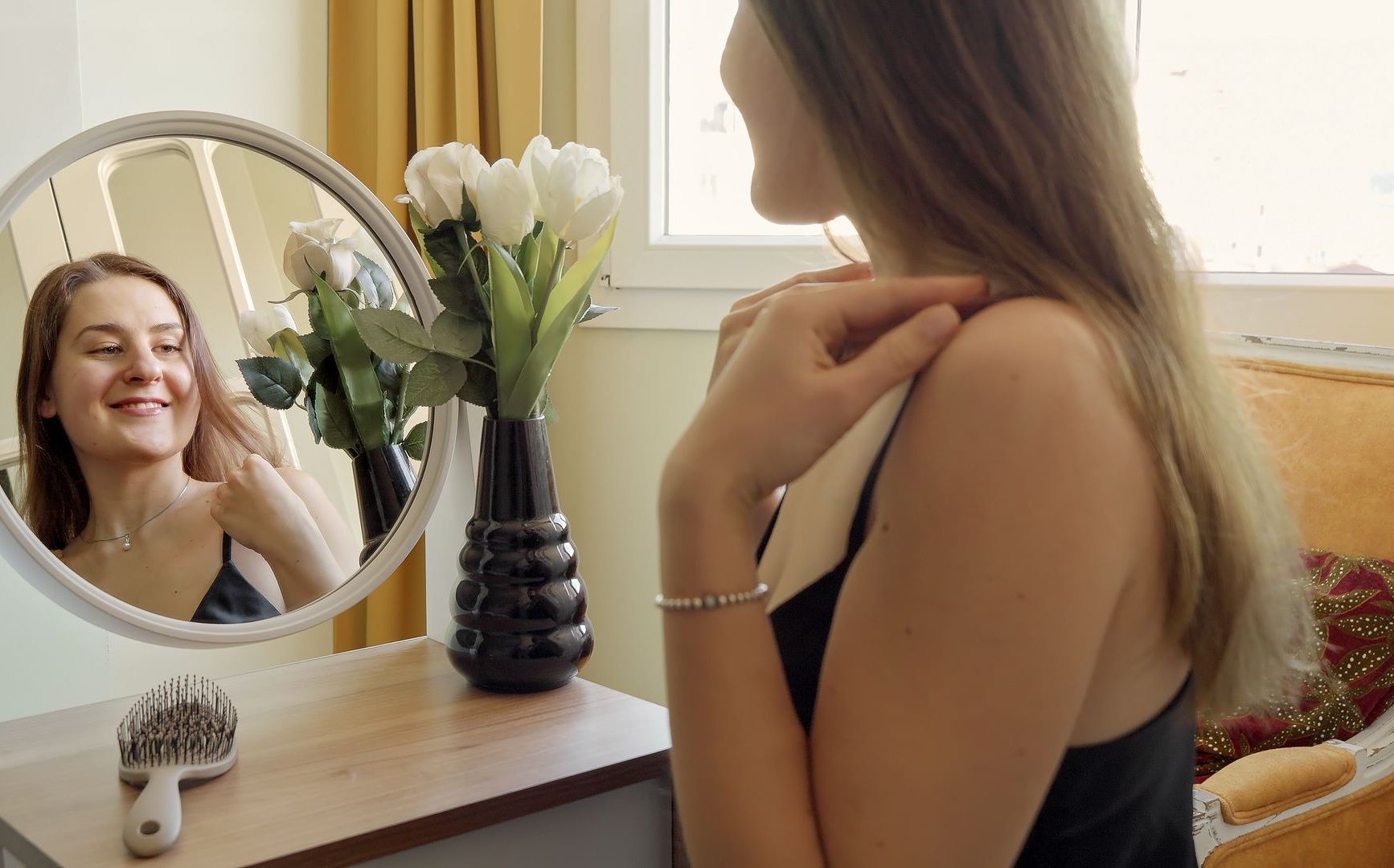 A woman is brushing her hair in front of a mirror.