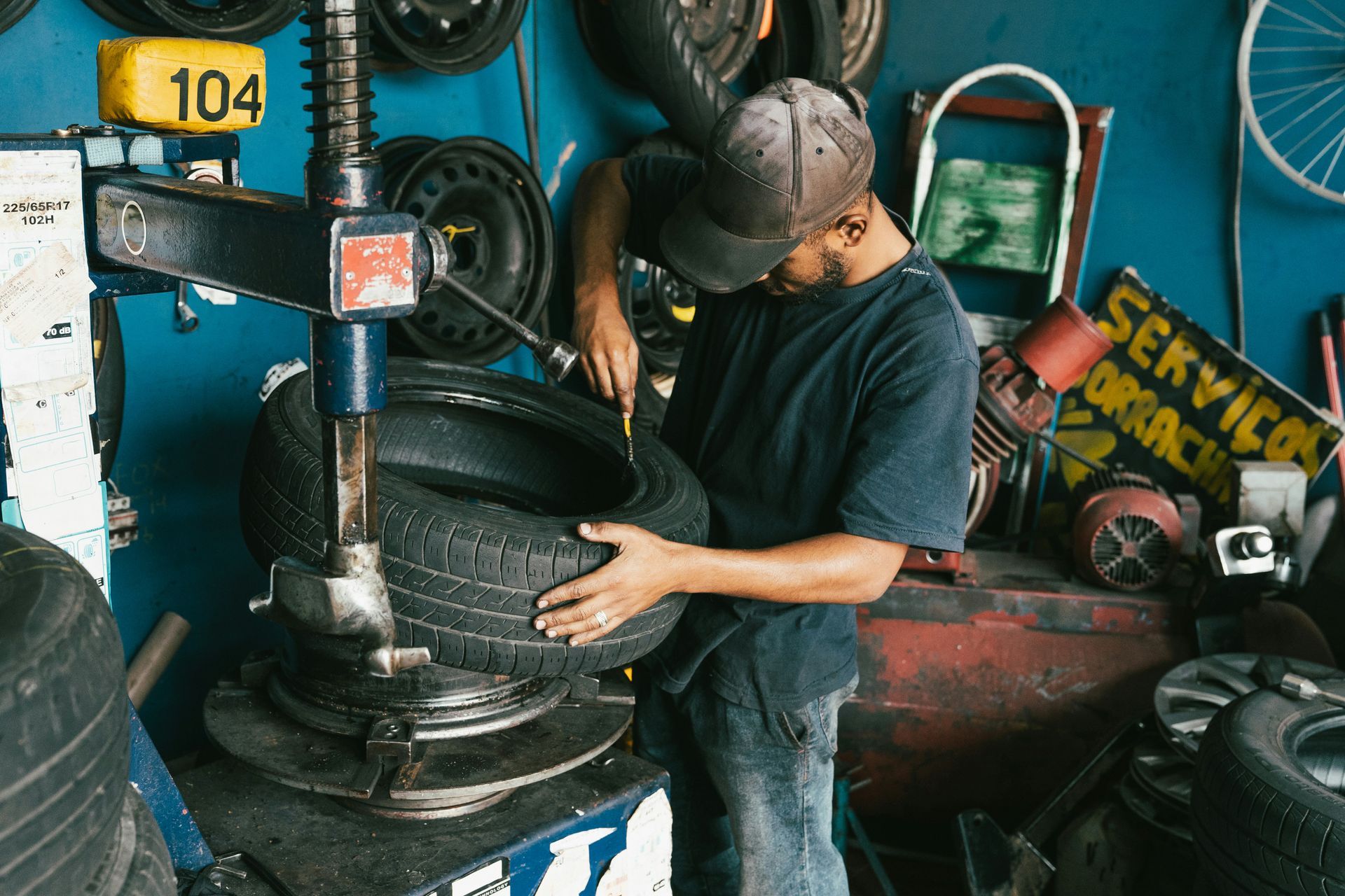 A man is changing a tire on a machine in a garage.