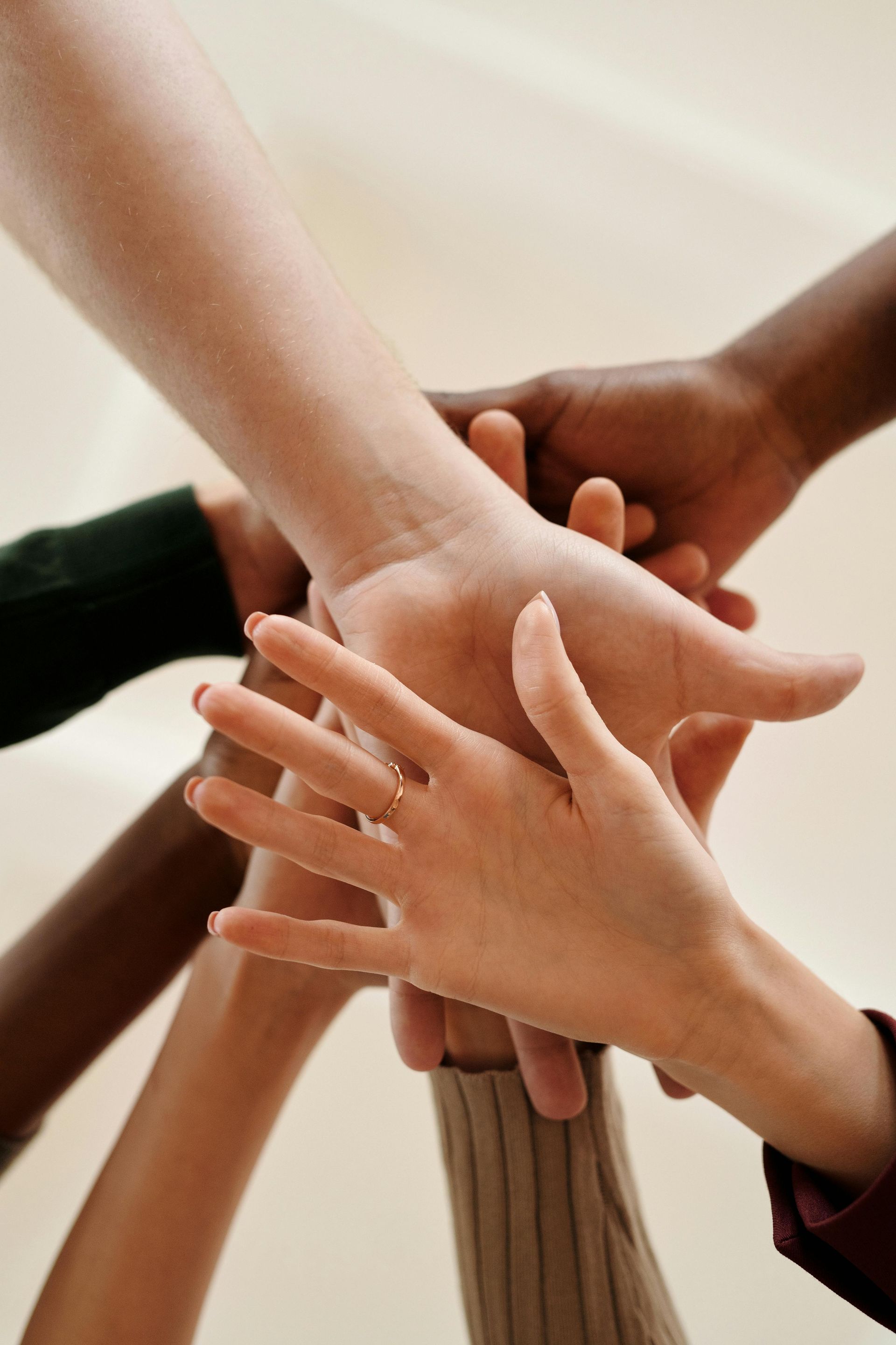 A diverse group of people are touch hands in a circle