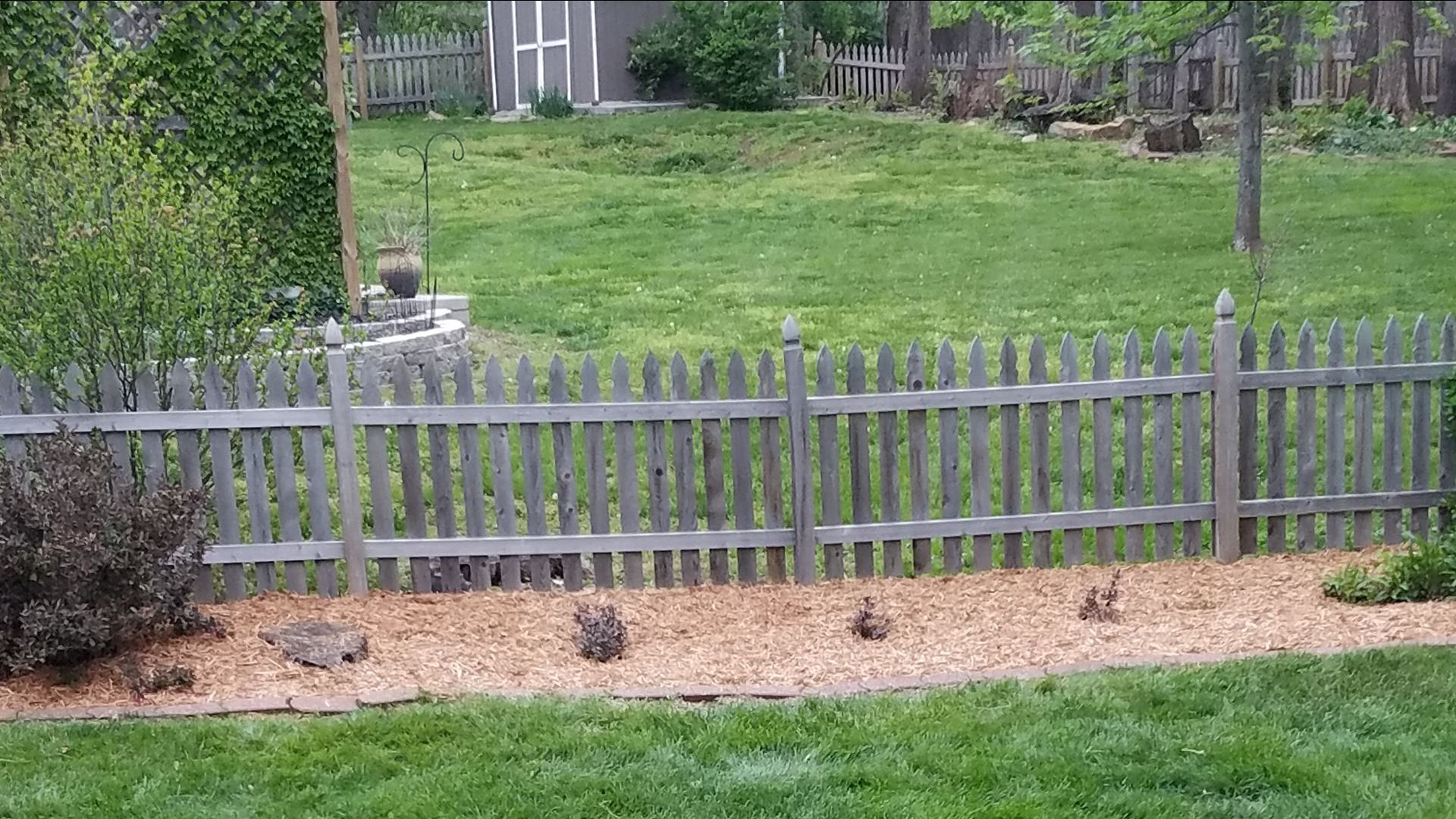 A wooden picket fence surrounds a lush green yard.