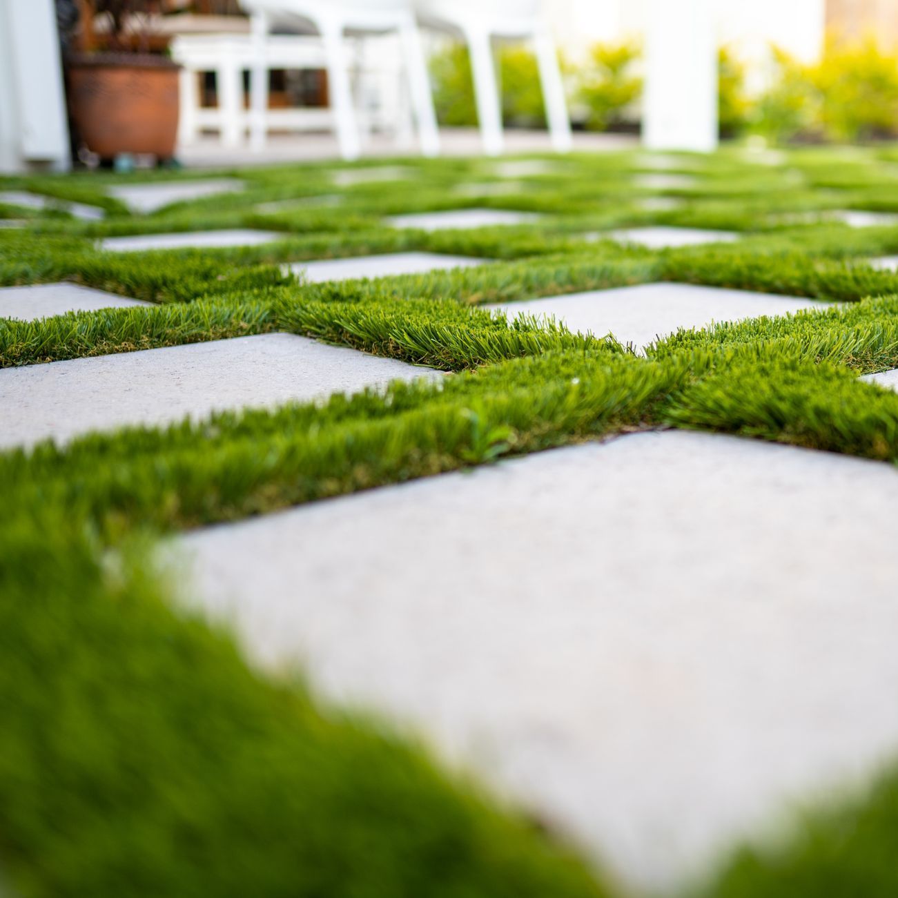A close up of a patio and concrete pavers with a lot of grass on it.