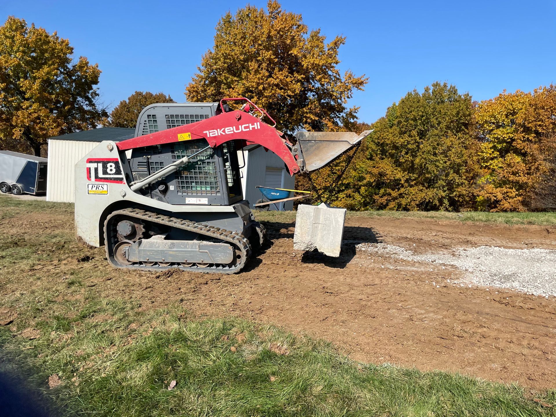 A bulldozer is sitting on top of a dirt field doing some hardscaping for a landscaping project