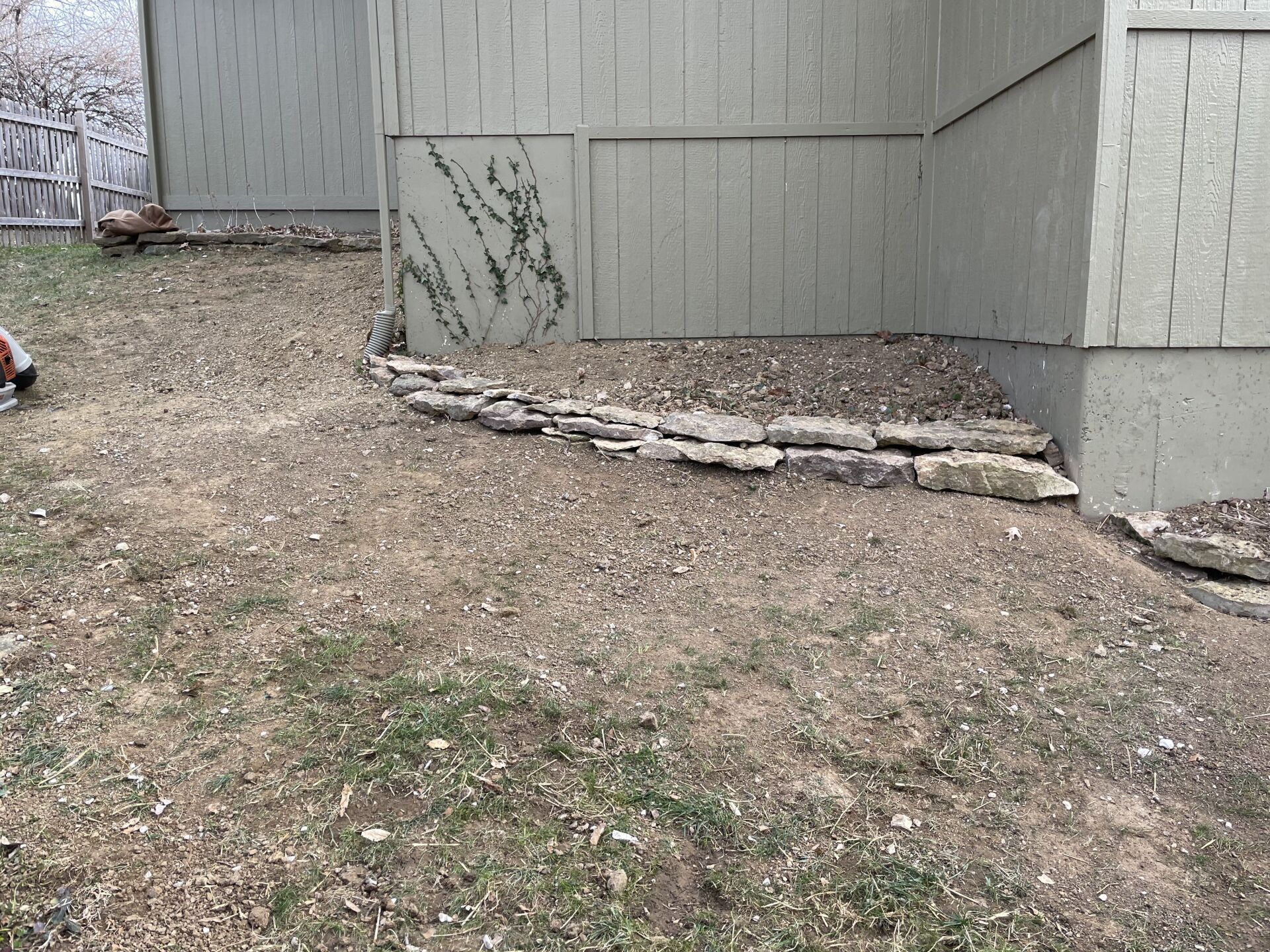 A person is standing in a yard next to a building.