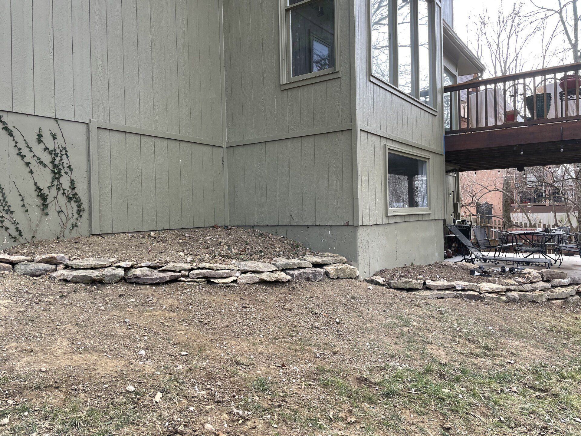 A house with a deck and a stone wall in front of it.