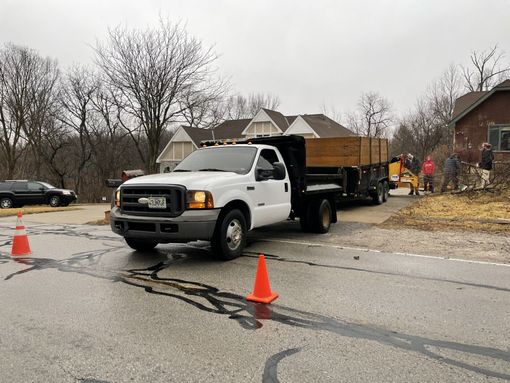 A white truck is driving down a street next to an orange cone.