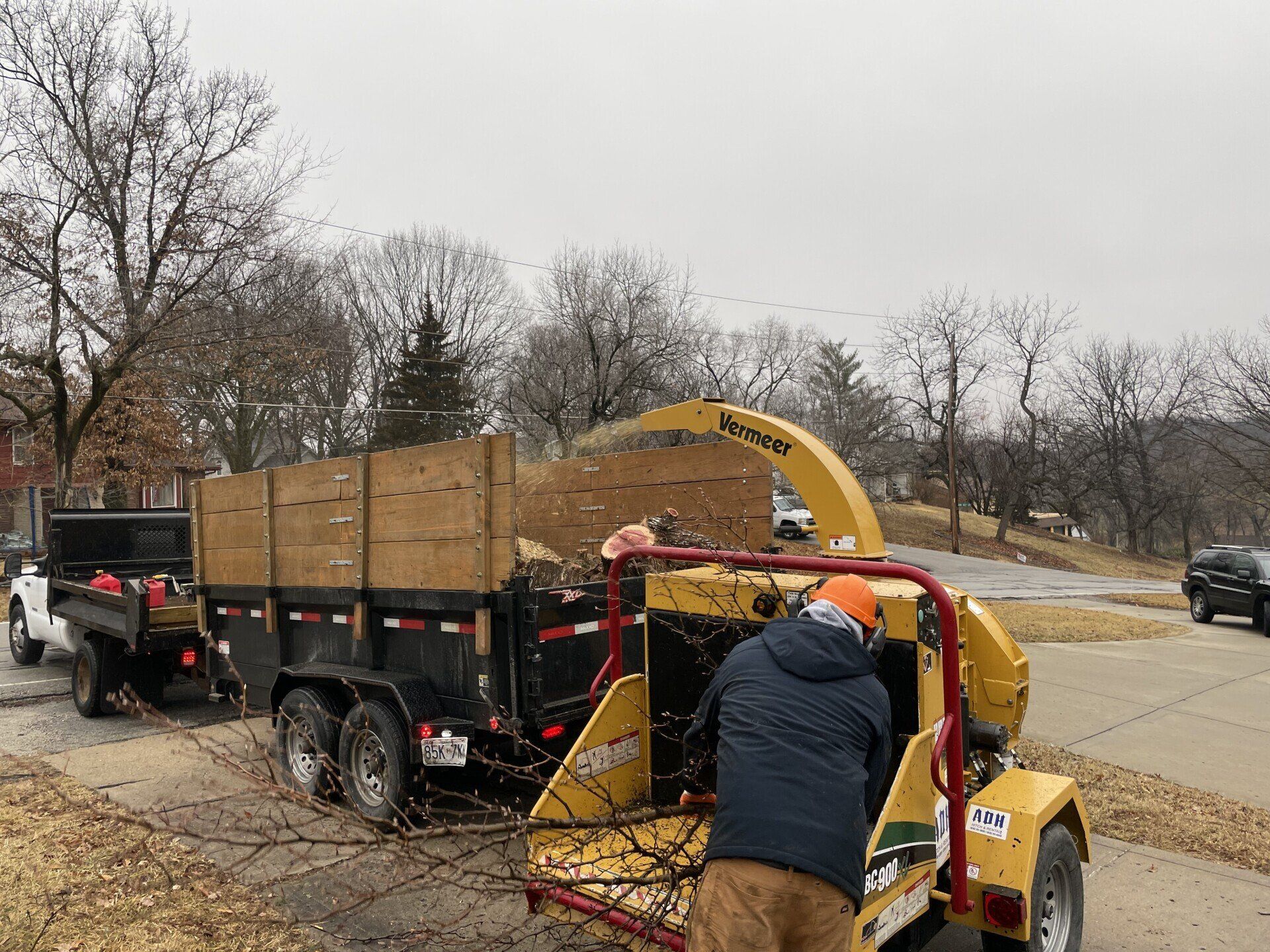 A man is working on a tree chipper on a trailer.
