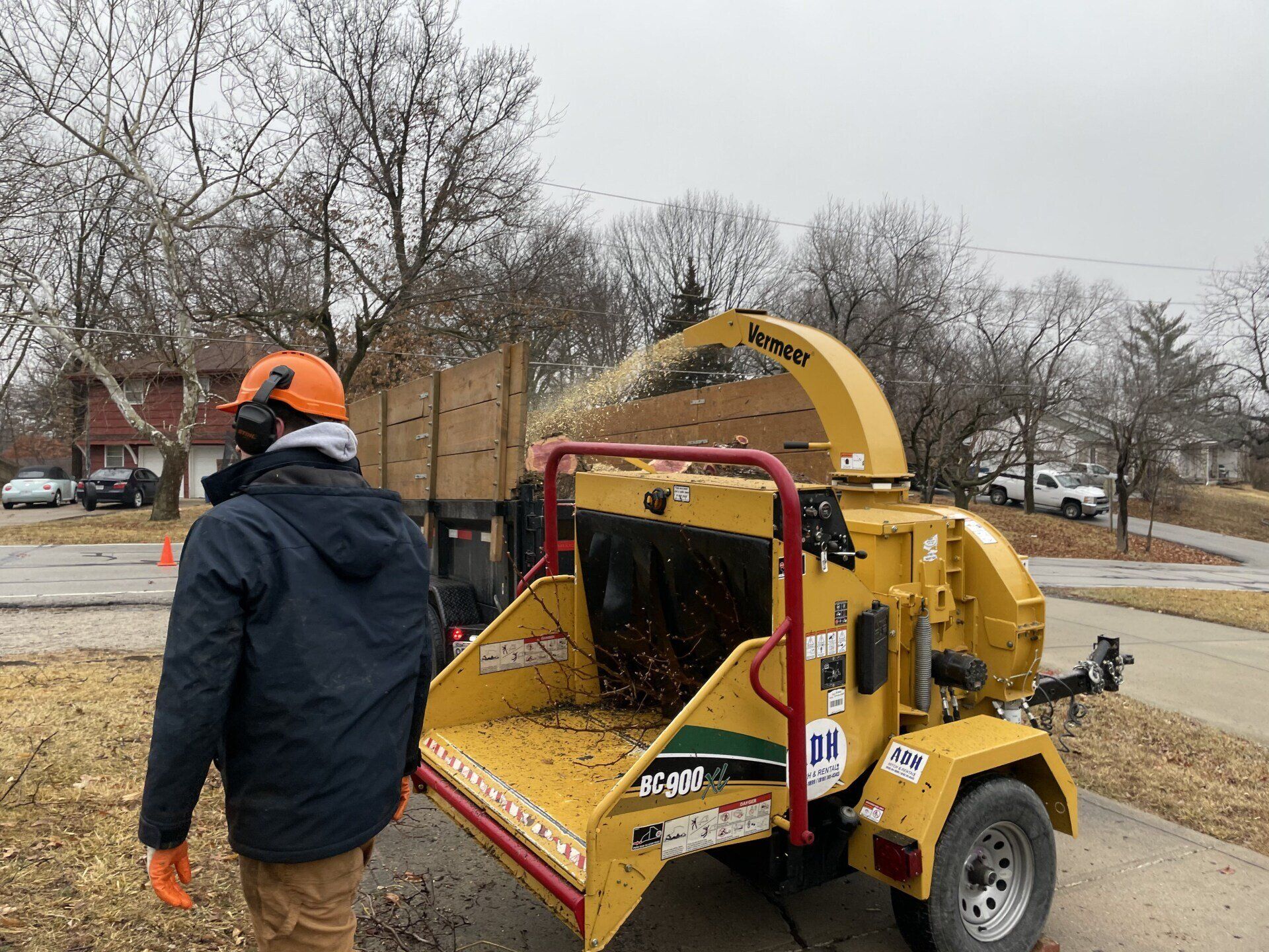 A man is standing next to a tree chipper.