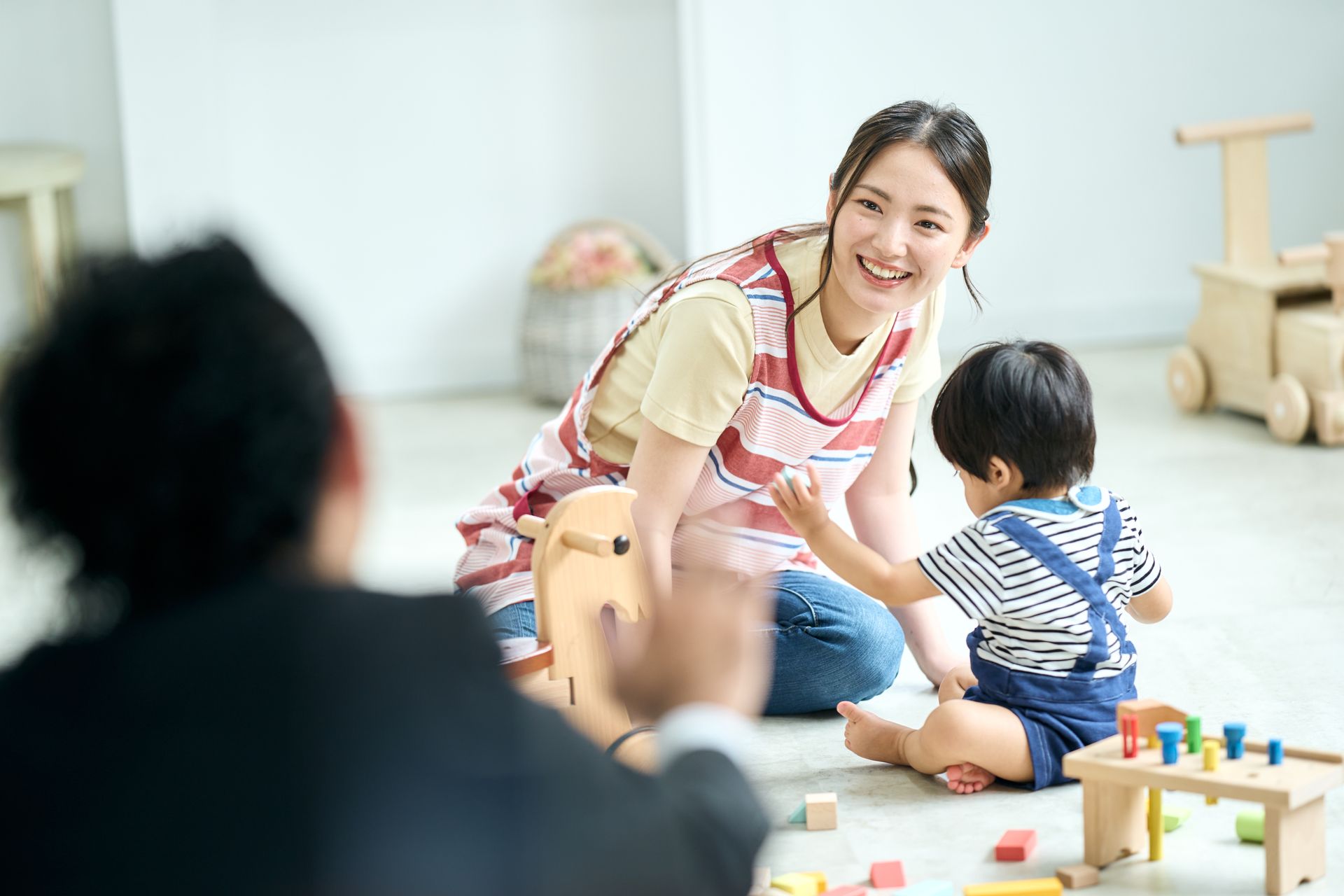 A woman is sitting on the floor playing with a child.