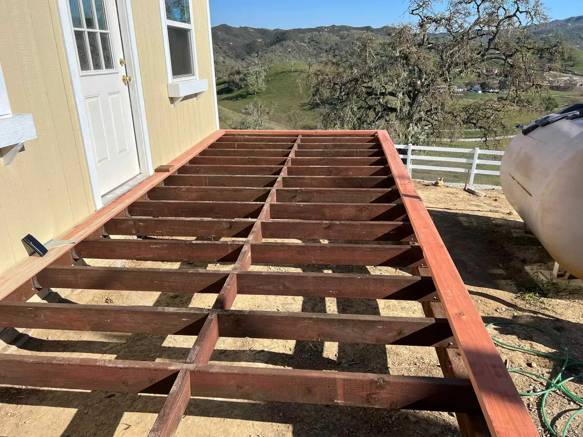 A wooden deck is being built on the side of a house.