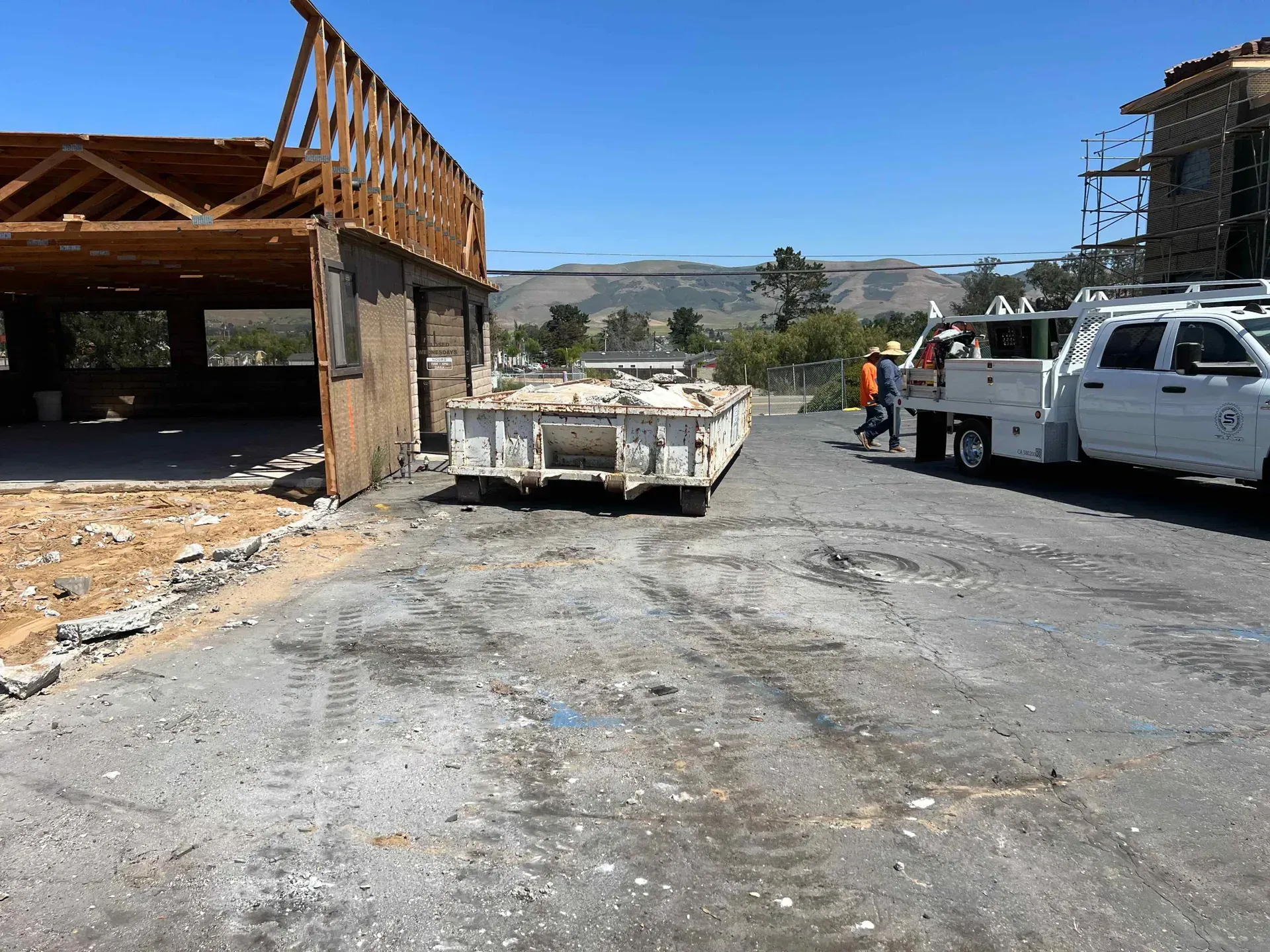 A dumpster is sitting in a parking lot next to a truck