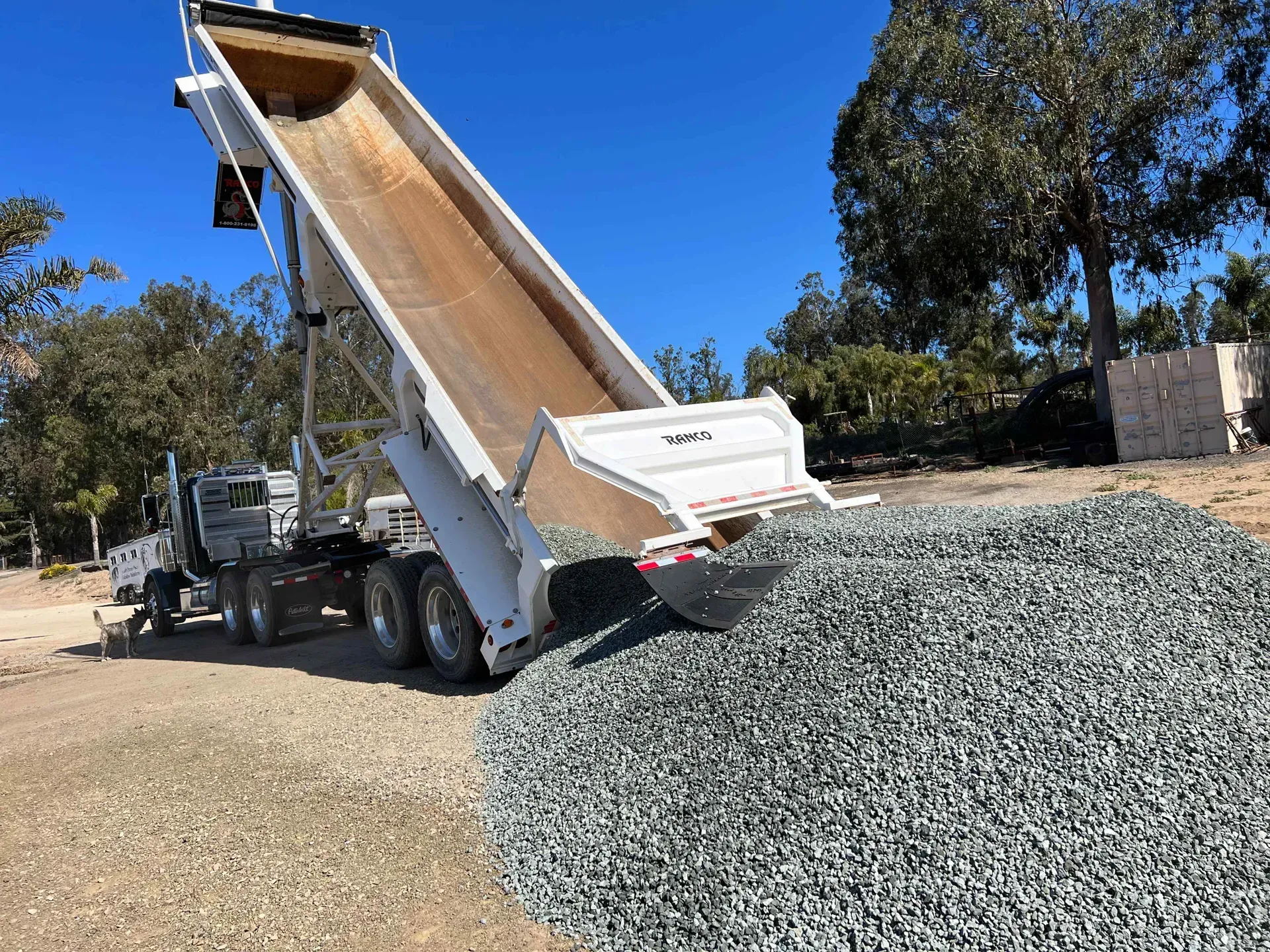 A dump truck is dumping gravel into a pile.