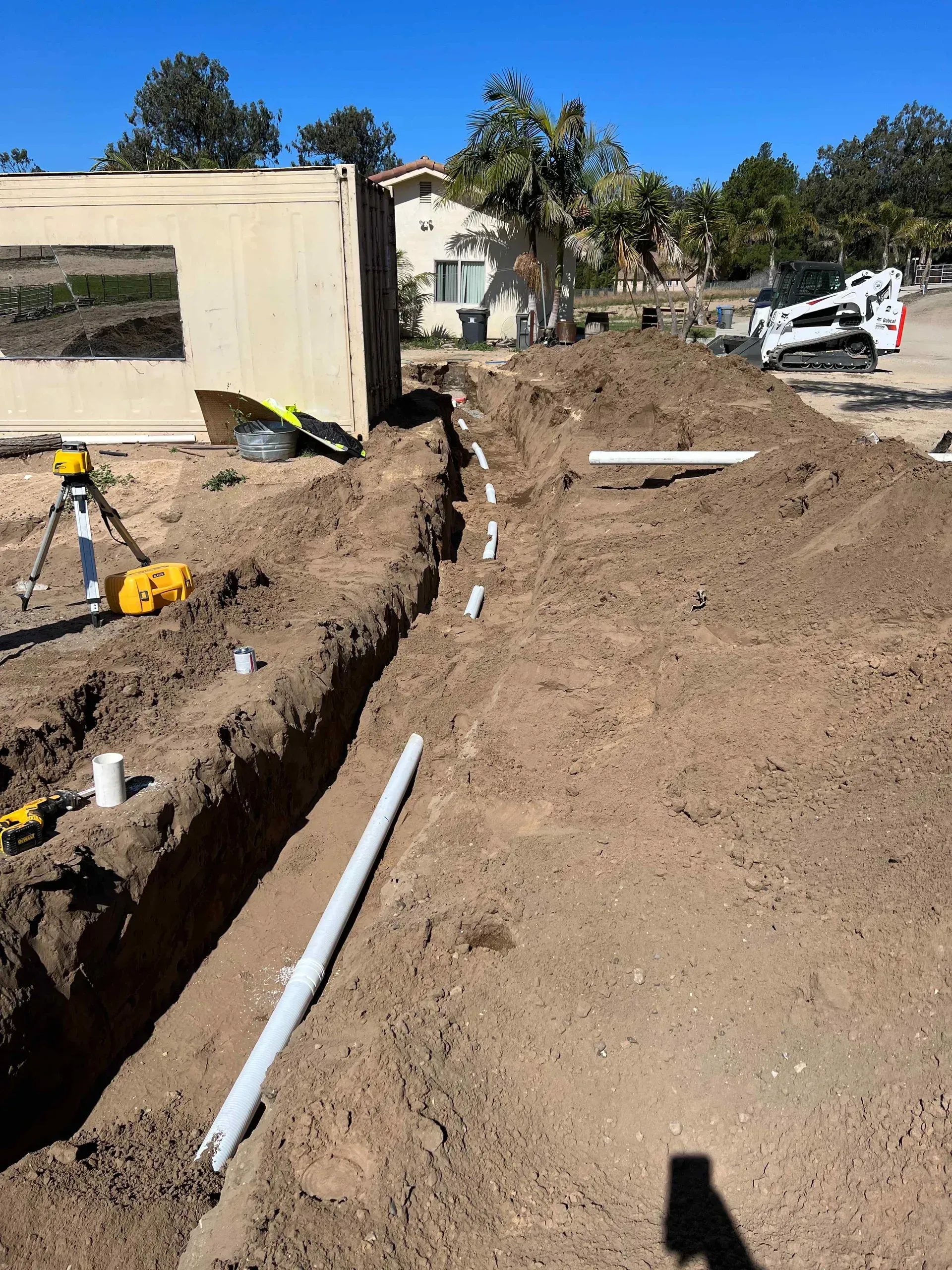 A construction site with a lot of pipes in the dirt.