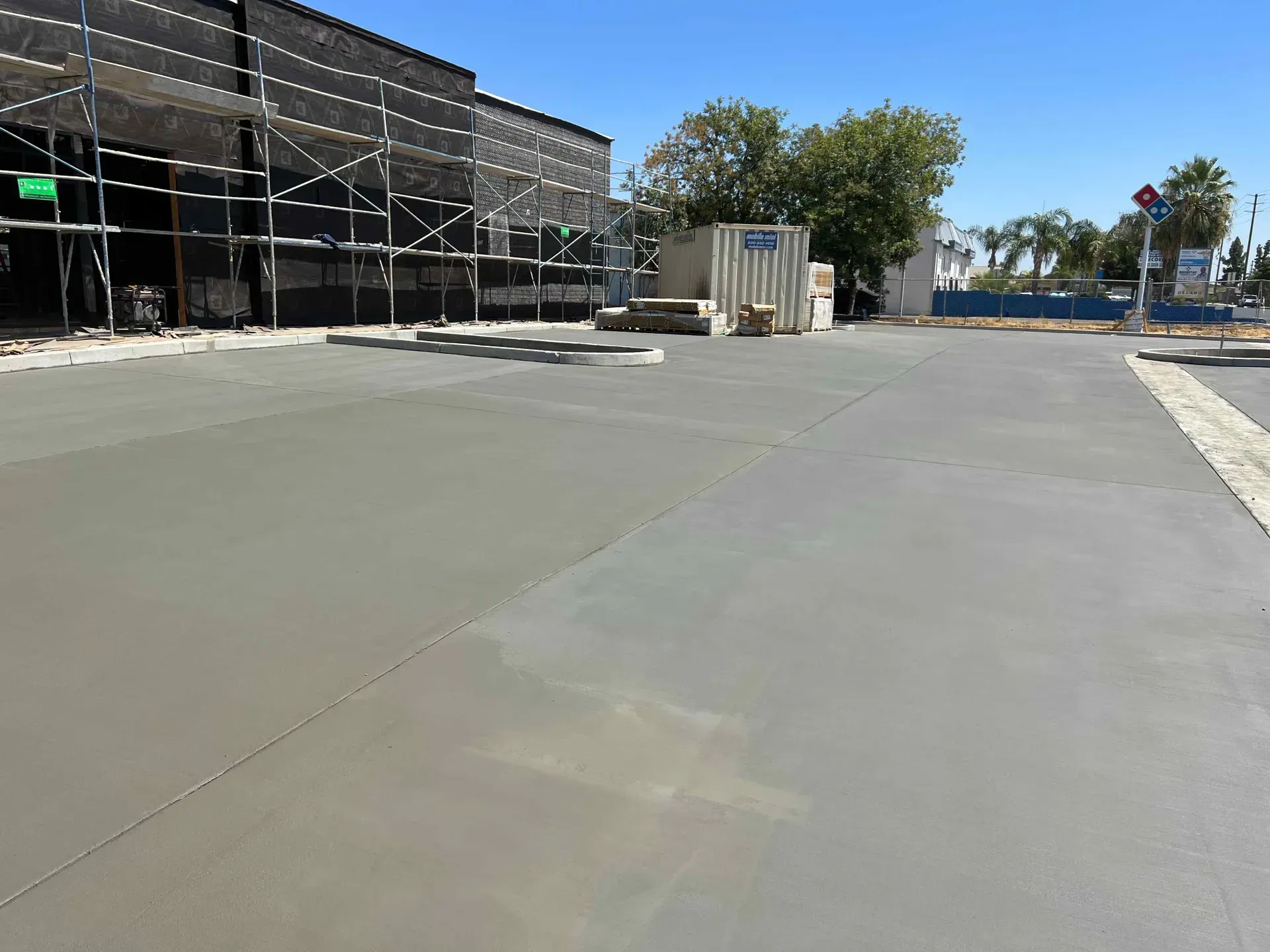 A concrete driveway is being built in front of a building under construction.