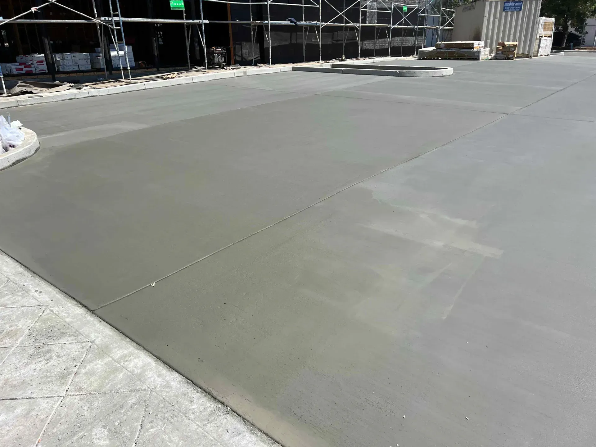 A concrete driveway is being built next to a building under construction.