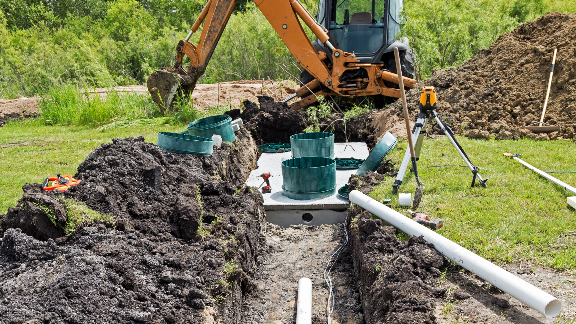 A tractor is digging a hole in the ground to install a septic system.
