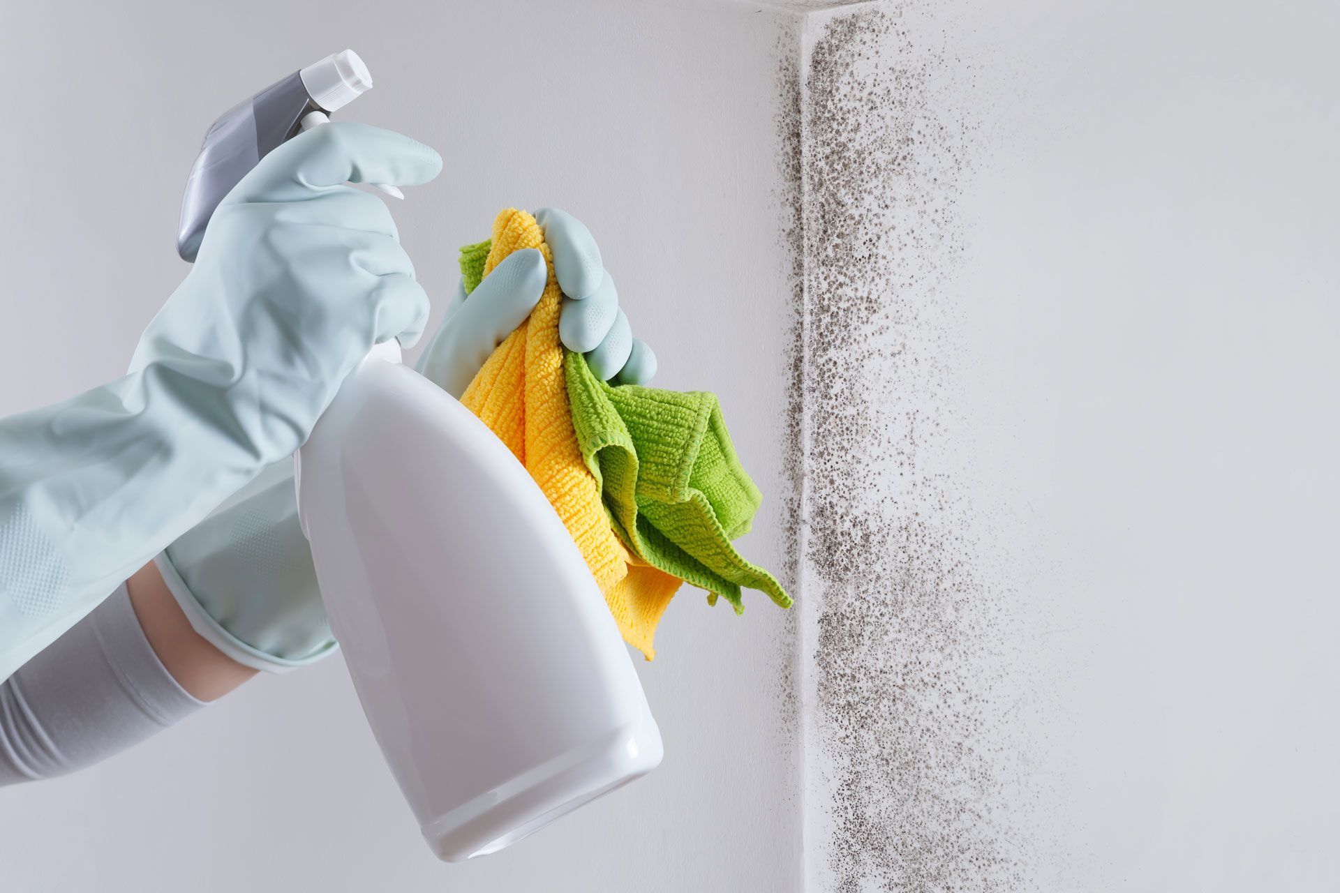 A person is cleaning a wall with a spray bottle and a towel.