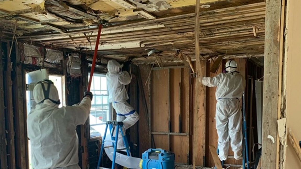 A group of people are working on the ceiling of a house.