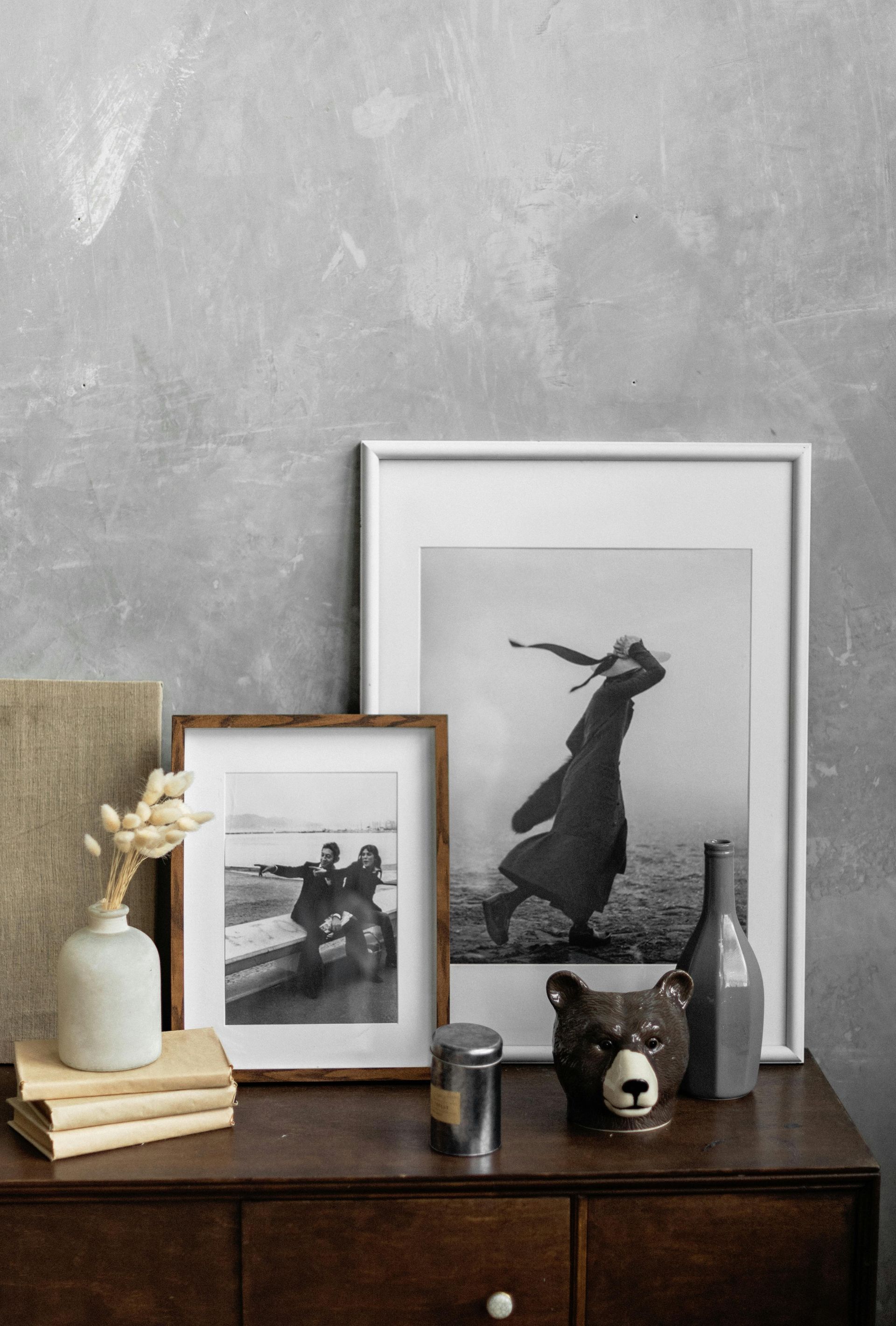 A dresser with a couple of framed pictures on it.