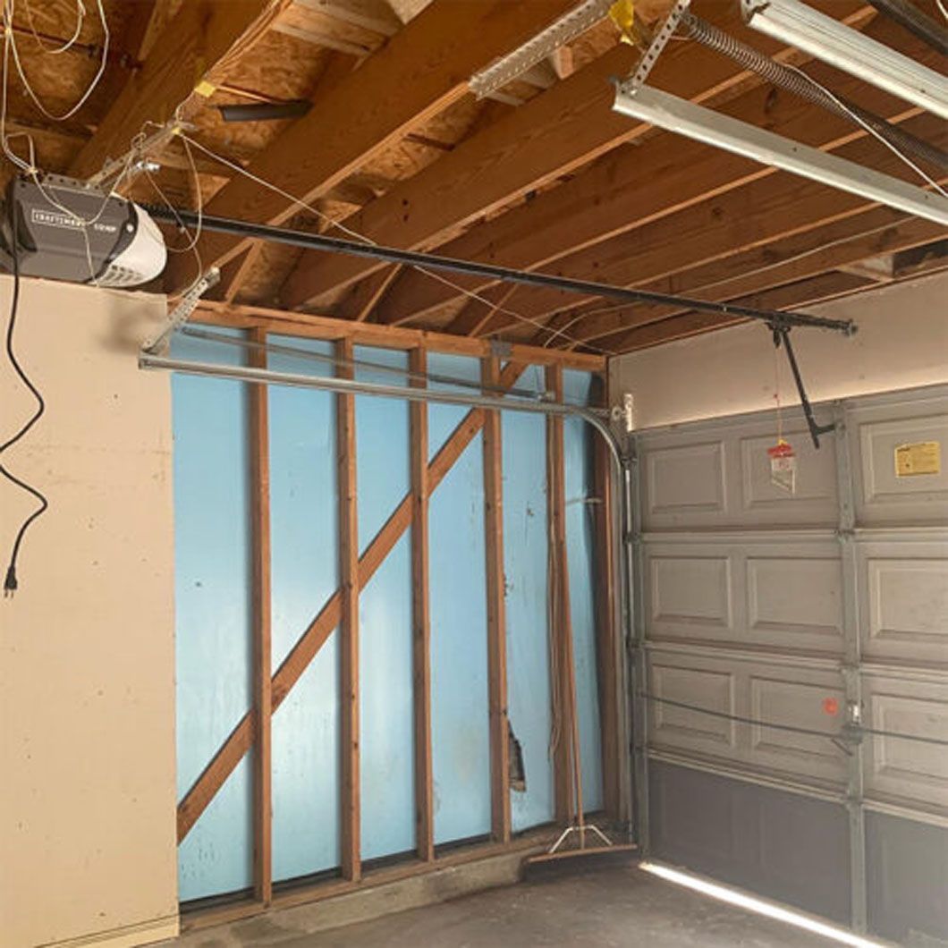 A garage with a broken wall and a garage door open