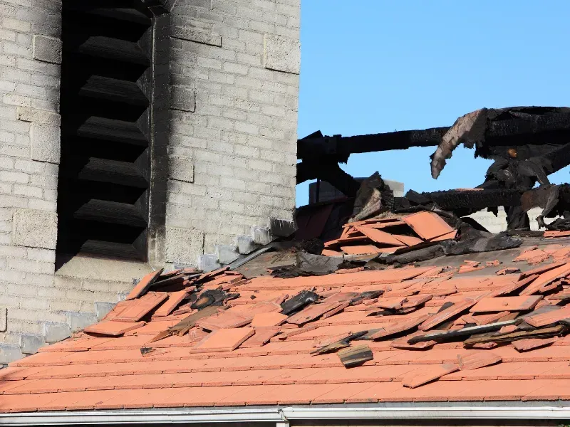 A brick building with a roof that has been damaged by a fire.