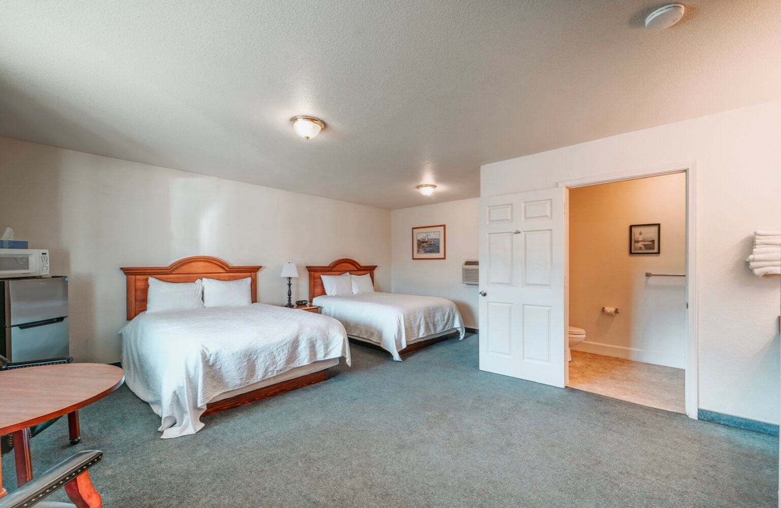 Hotel room with two beds, a microwave, and a bathroom.