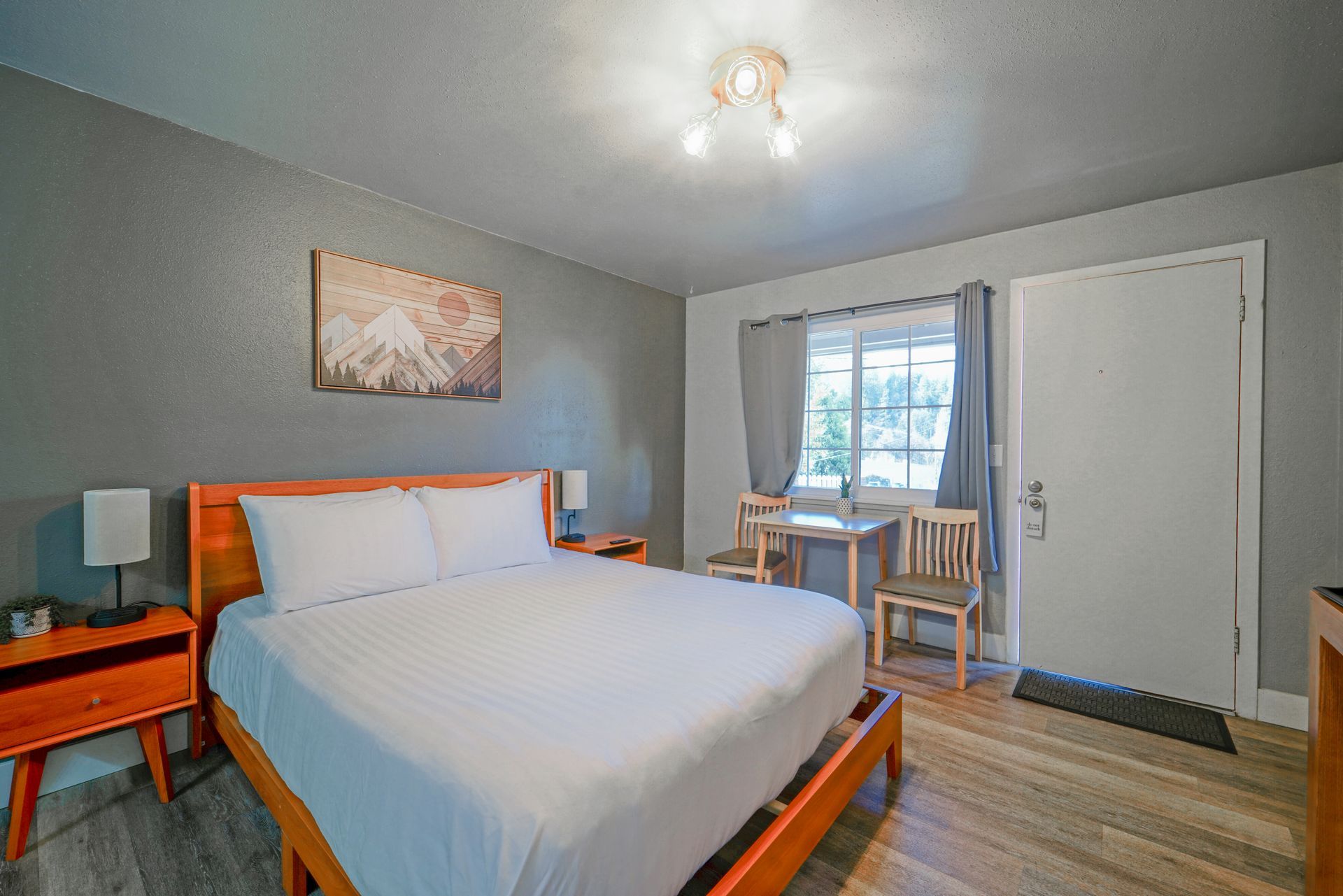 Bedroom with wooden bed frame, nightstand, green accent wall, and mountain art.